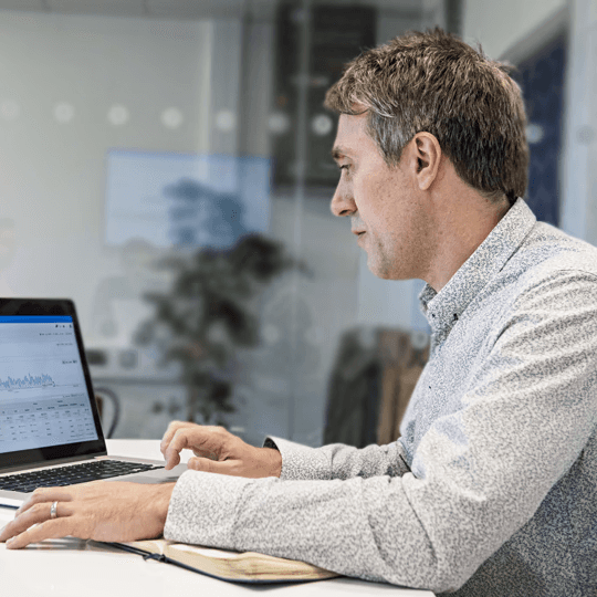 Male worker analysing project data on a laptop computer