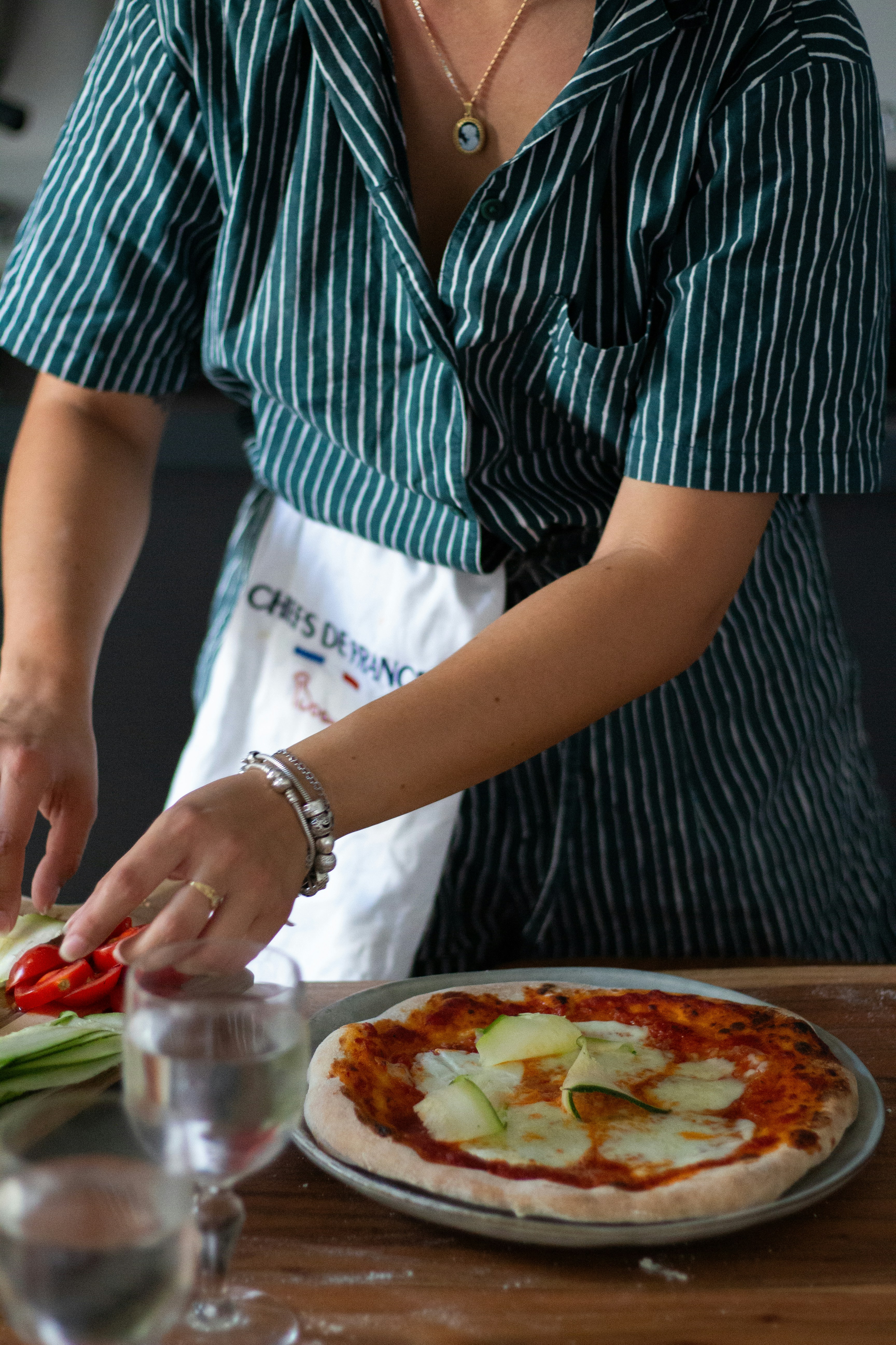 a woman cutting up a pizza on top of a wooden table