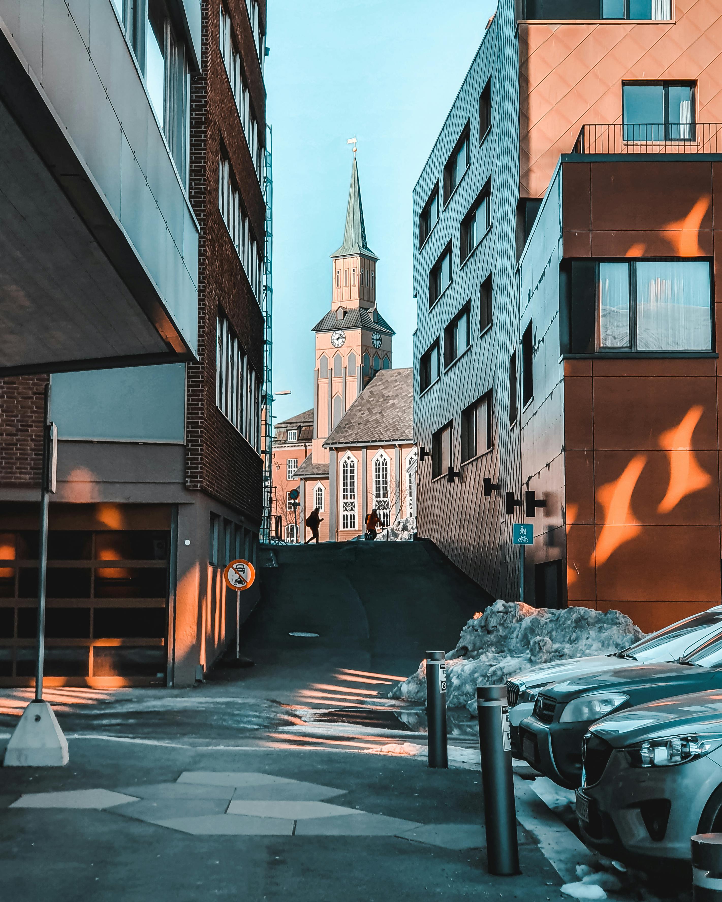 Smiling woman in glasses talking on a smartphone while working on a laptop at a desk.