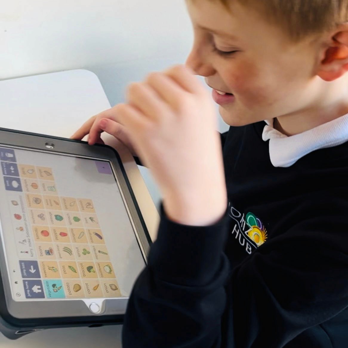 A child is using a tablet to play a game where they can choose fruit and vegetables to add to a shopping list. They are enjoying using the tablet.