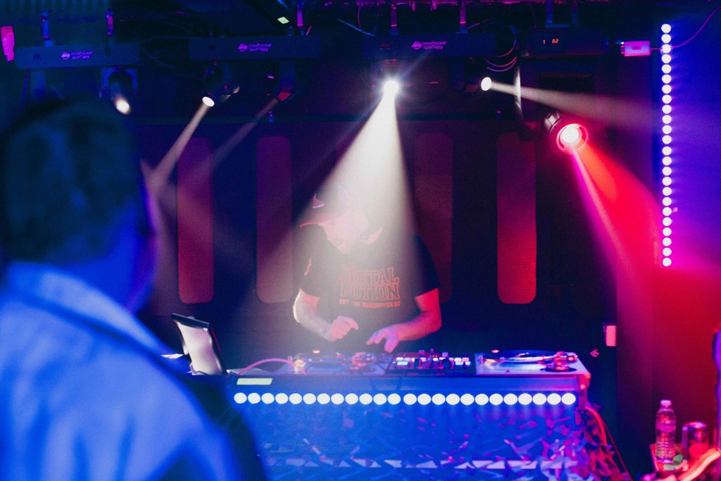 Image of a DJ playing with lights shining down.