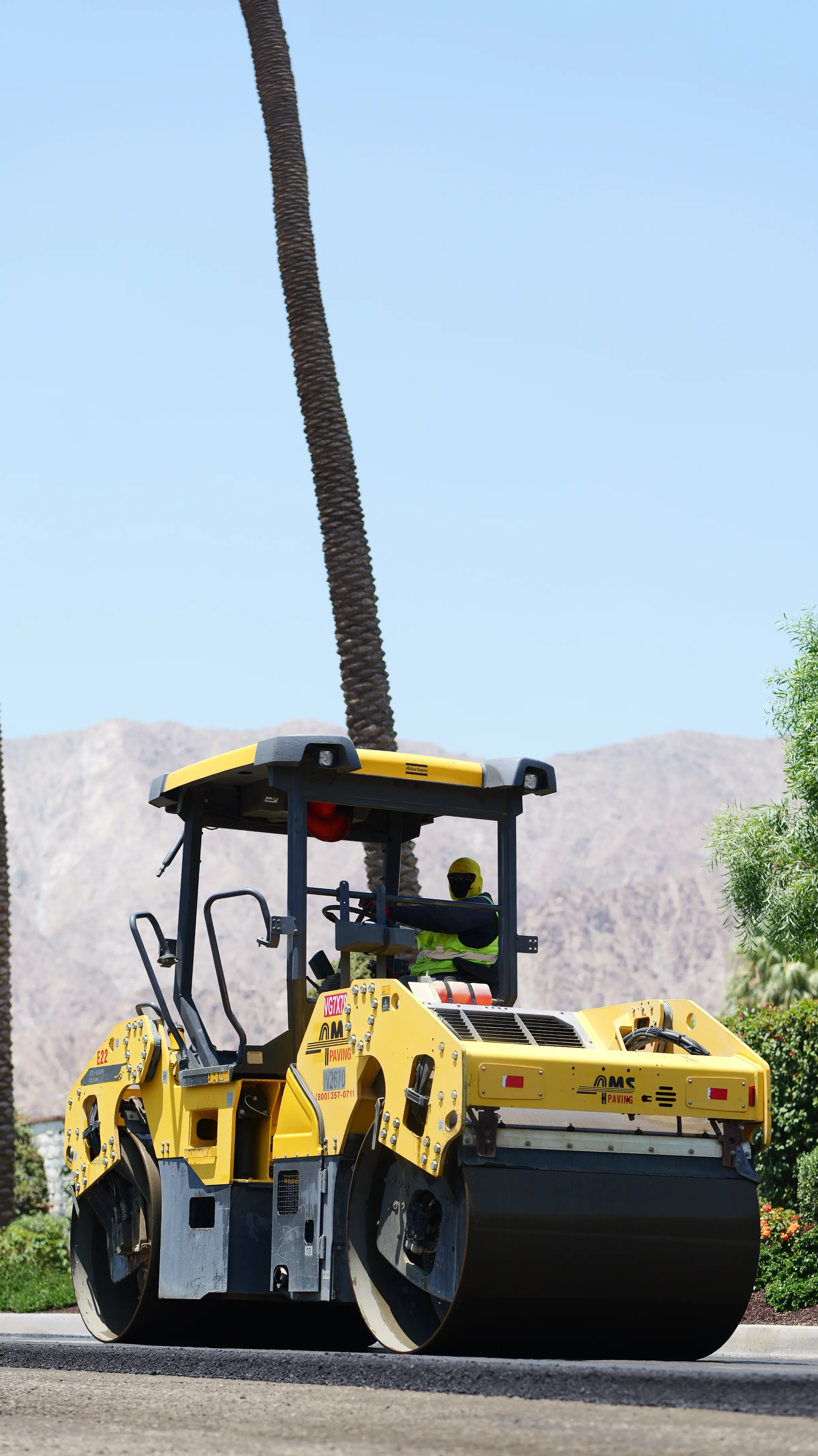 Rollerman using roller to compact new asphalt pavement