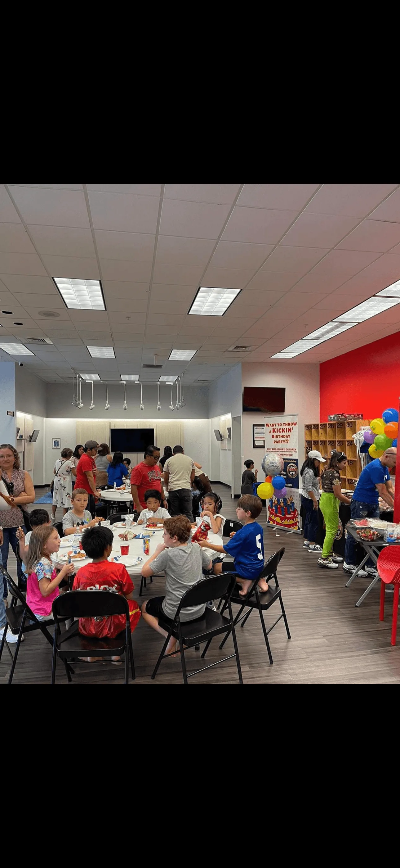 Children sitting at round table have lunch at birthday party.
