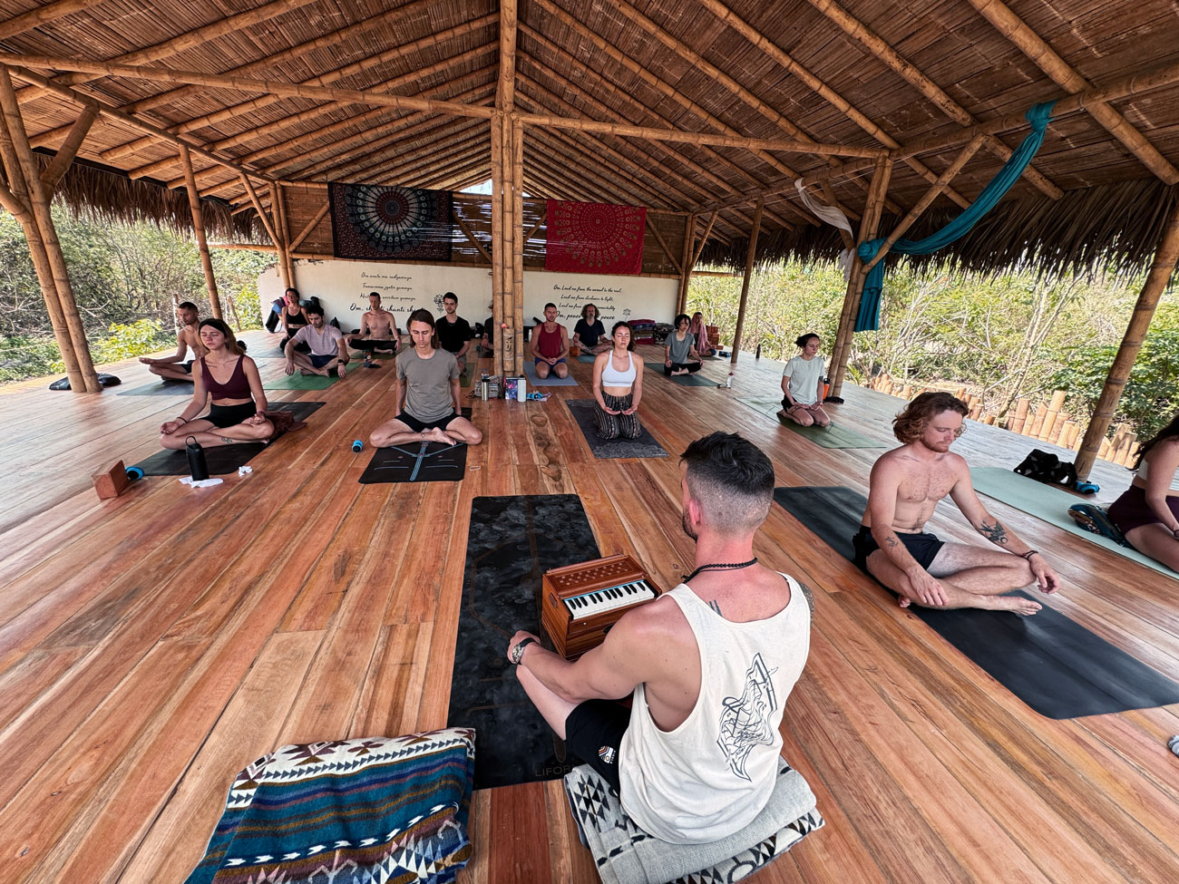 Group yoga retreat participants practicing together in a jungle studio.