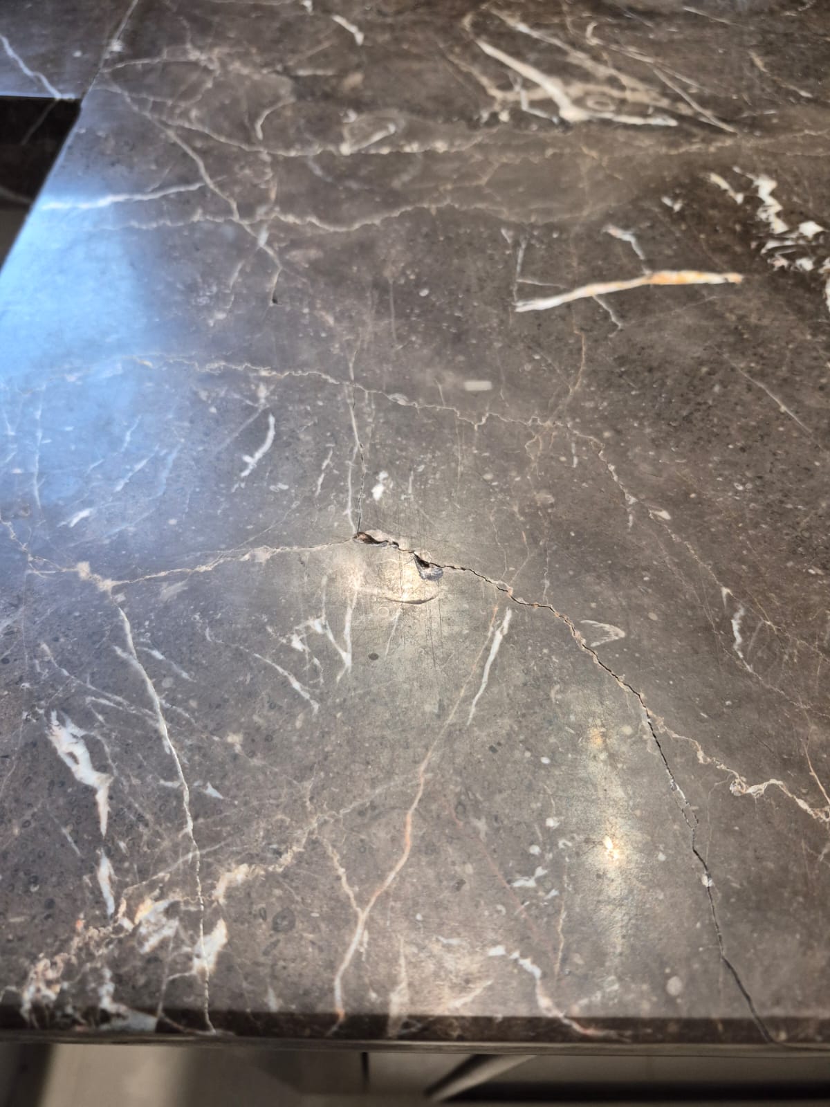 Impact-damaged dark marble vanity worktop before repair in Dubai