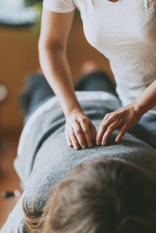 Un chiropracteur effectuant un ajustement sur le dos d’une patiente, utilisant des techniques de pression ciblées pour soulager les tensions et améliorer l’alignement vertébral.