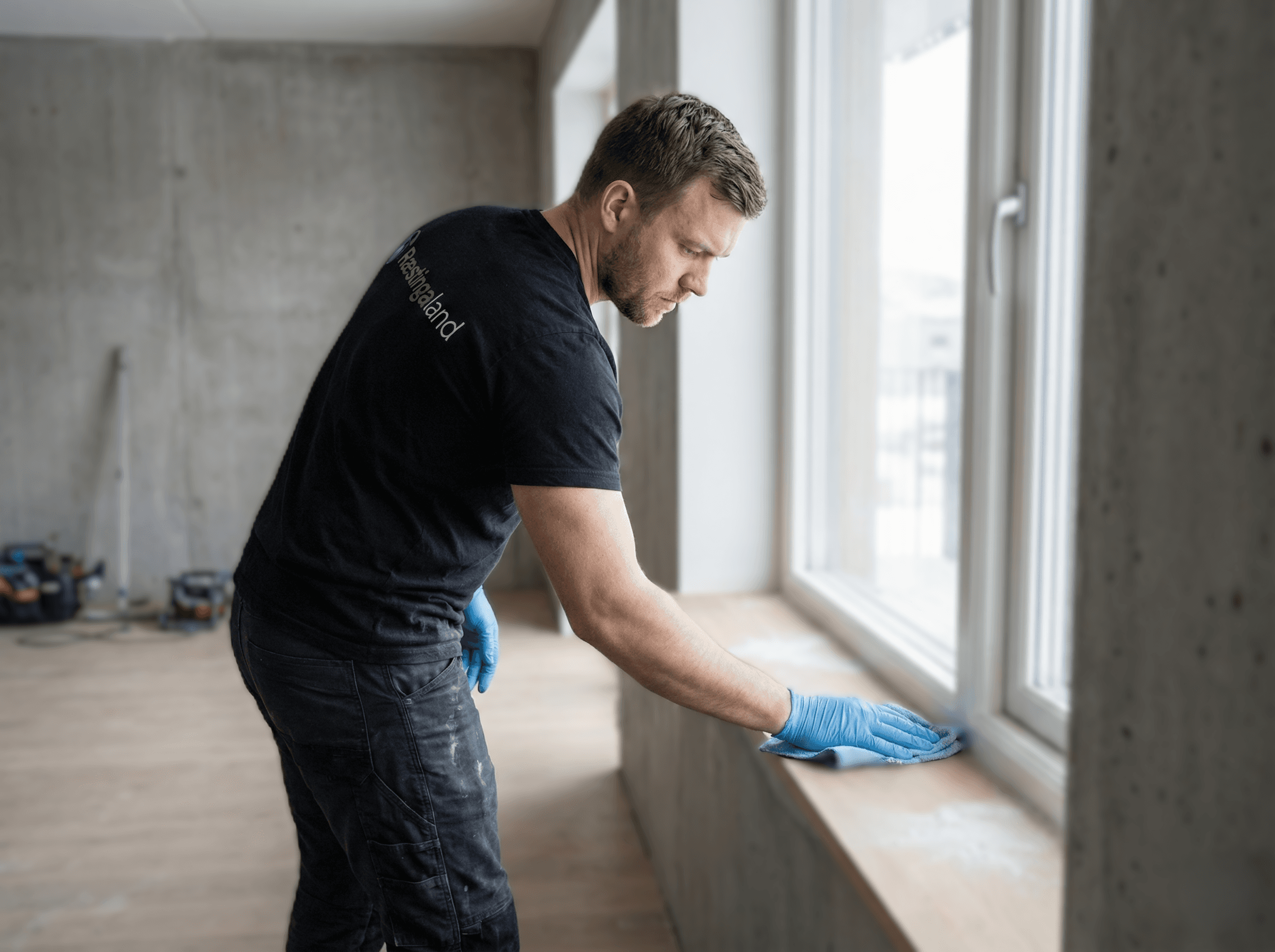 Fjarlæging á málningu af glugga með sköfu eftir framkvæmdir.