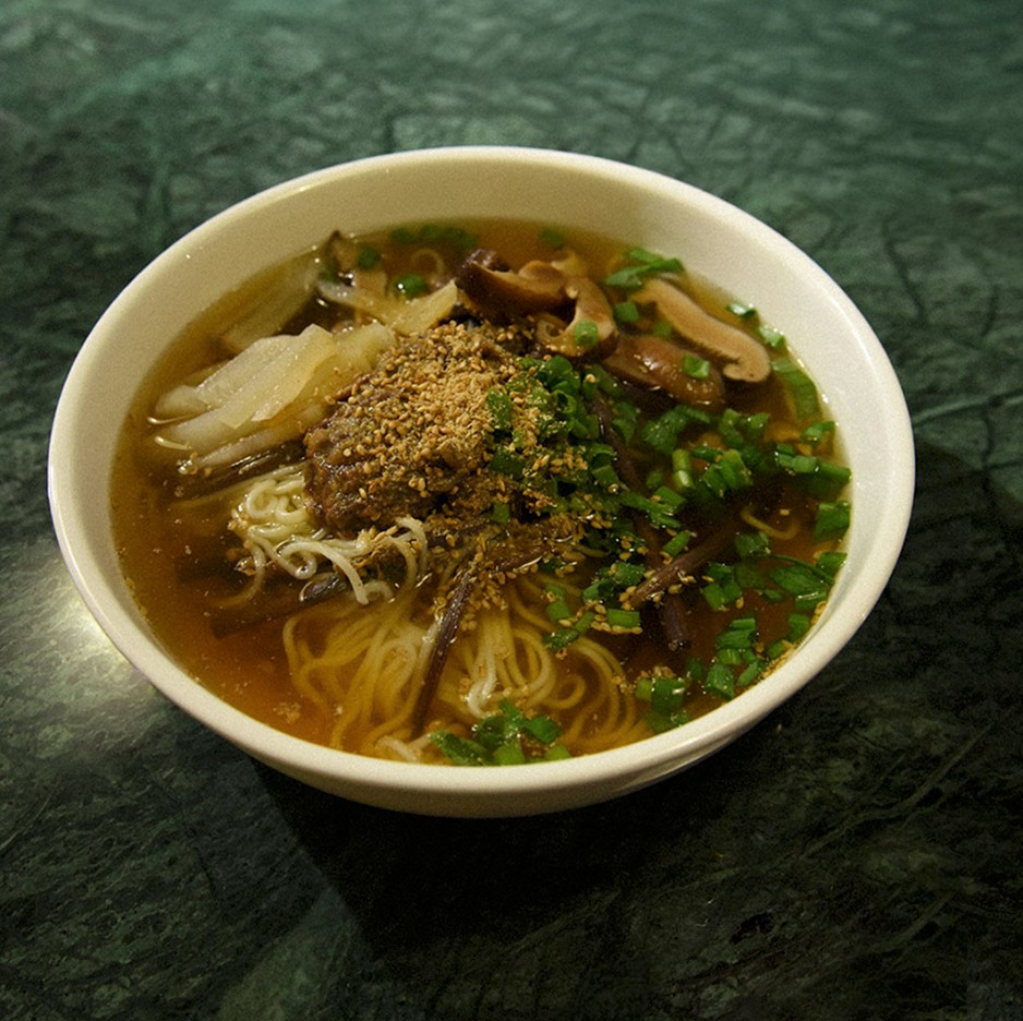 A cozy room with a wooden desk, computer, and warm sunlight streaming through a window.