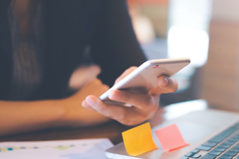 Business women hand are uses a smartphone and use a laptop computer in office.