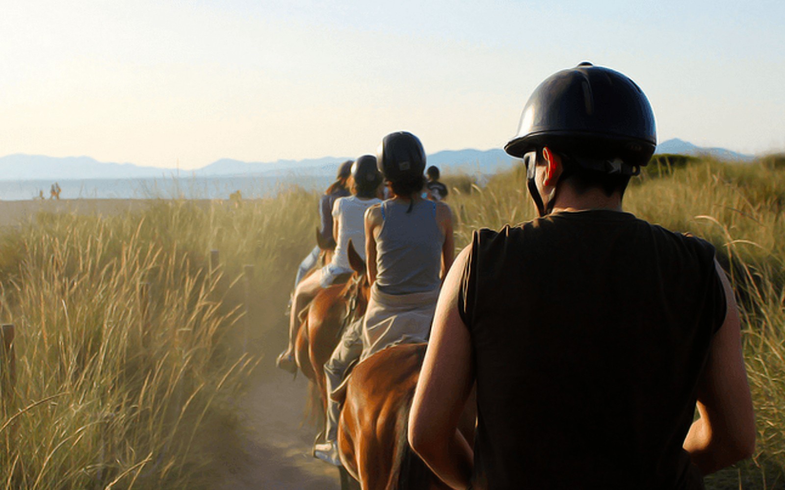 Paseo a caballo en grupo por un camino de playa en Mallorca.
