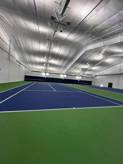Newly resurfaced indoor tennis court with vibrant lines and smooth flooring.
