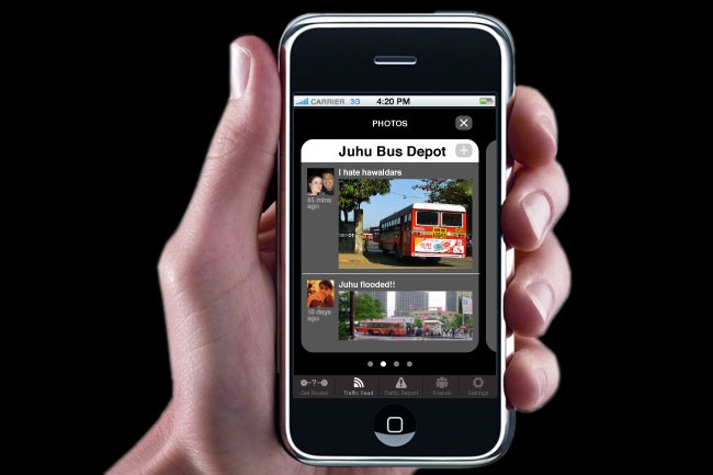 A hand holds a black iPhone displaying a photo app interface. The screen shows two photos: one of a red bus labeled “Juhu Bus Depot” and another of a person. The time displayed is 4:20 PM. The carrier is carrier 33. The app interface includes icons for call, home, mail, traffic, feedback, and settings.