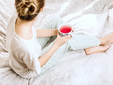 Mujer en pijama tomando té sentada en una cama