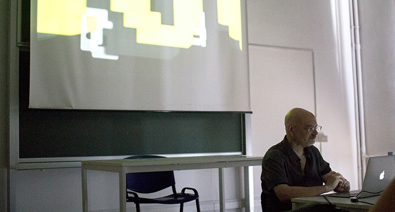 a man is presenting a course with an image projected on the wall behind him