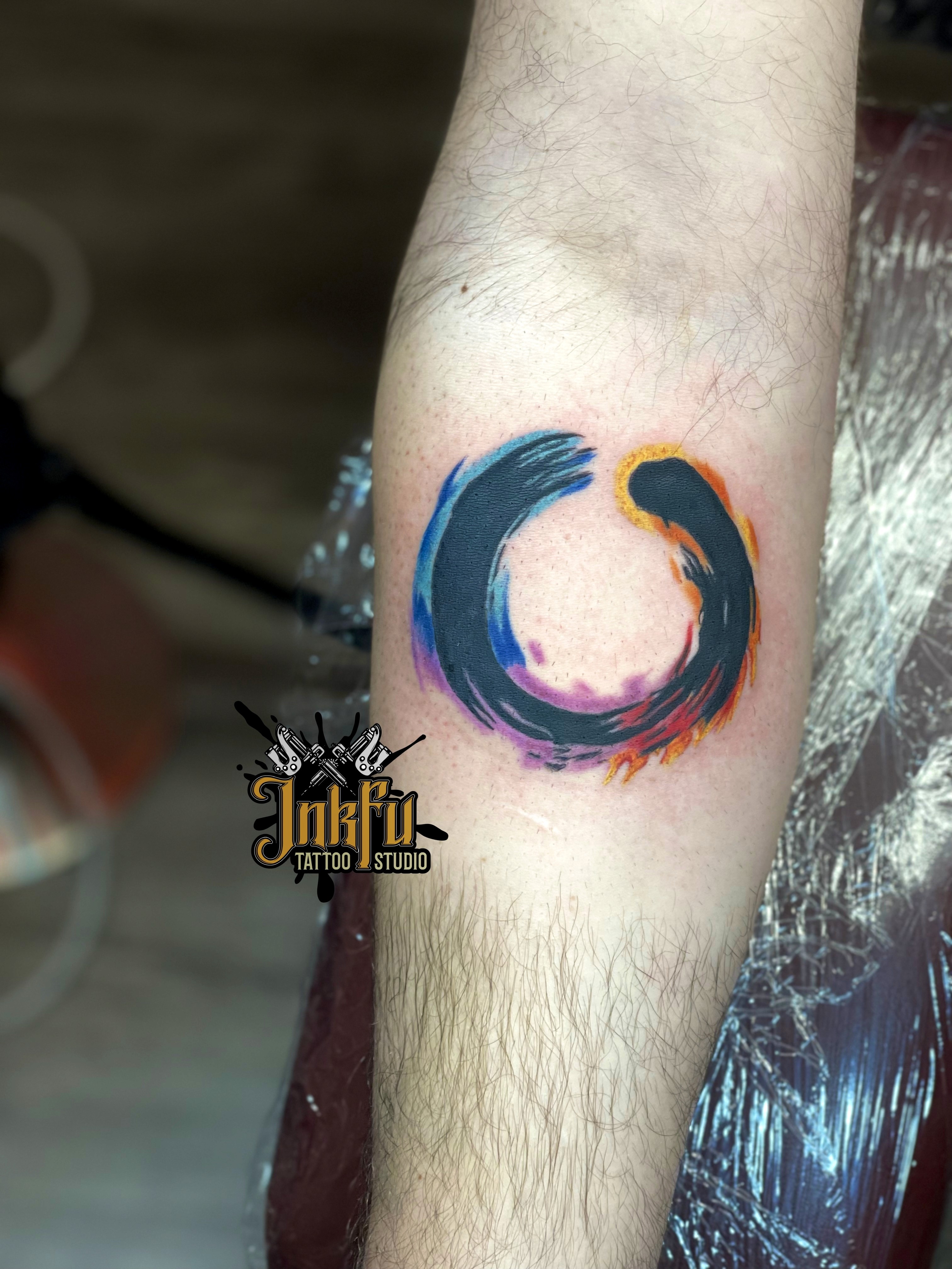 Color enso circle tattoo with watercolor accents on the forearm, by Meer Rich