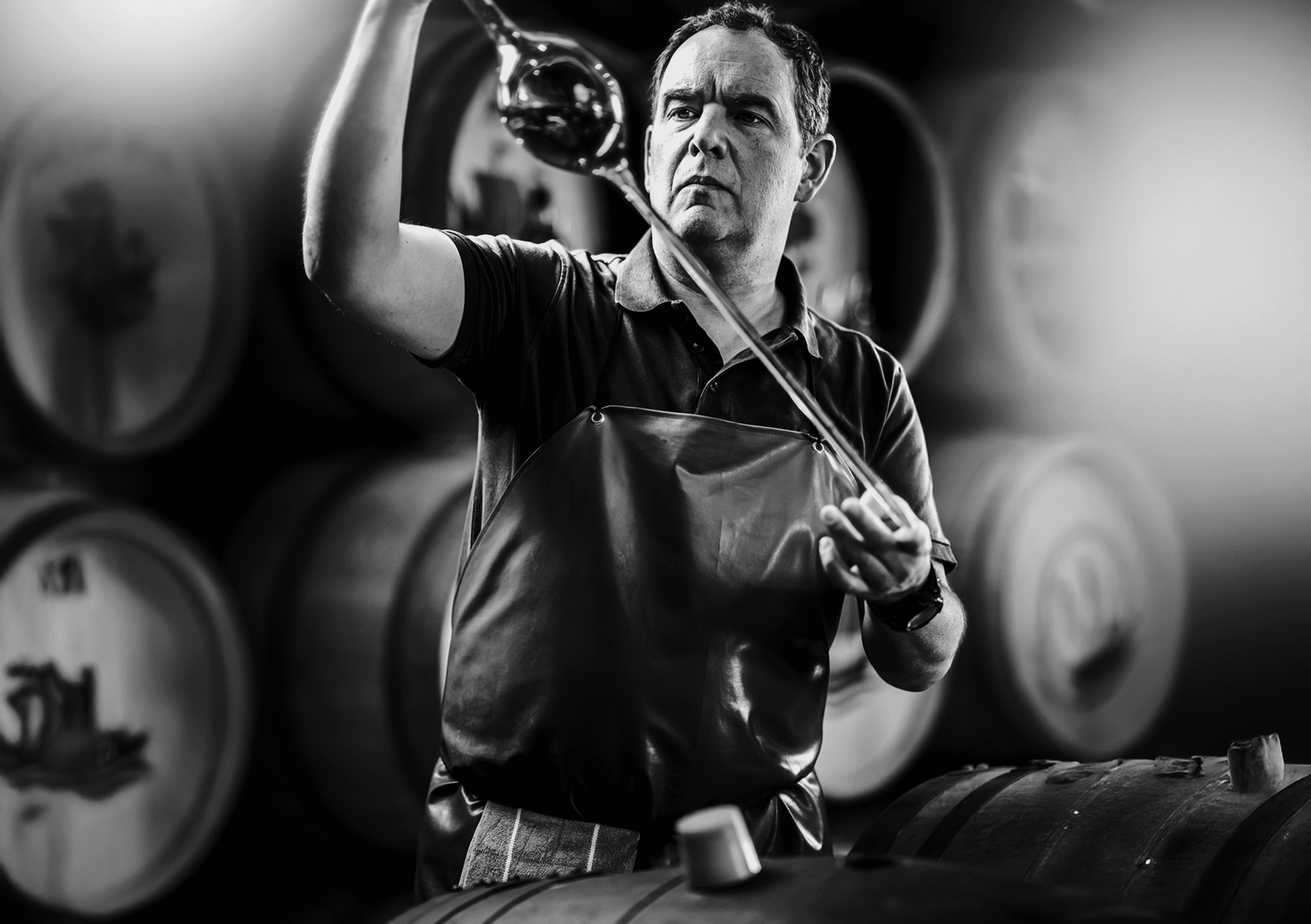 Man tastes liquid from glass in wine cellar