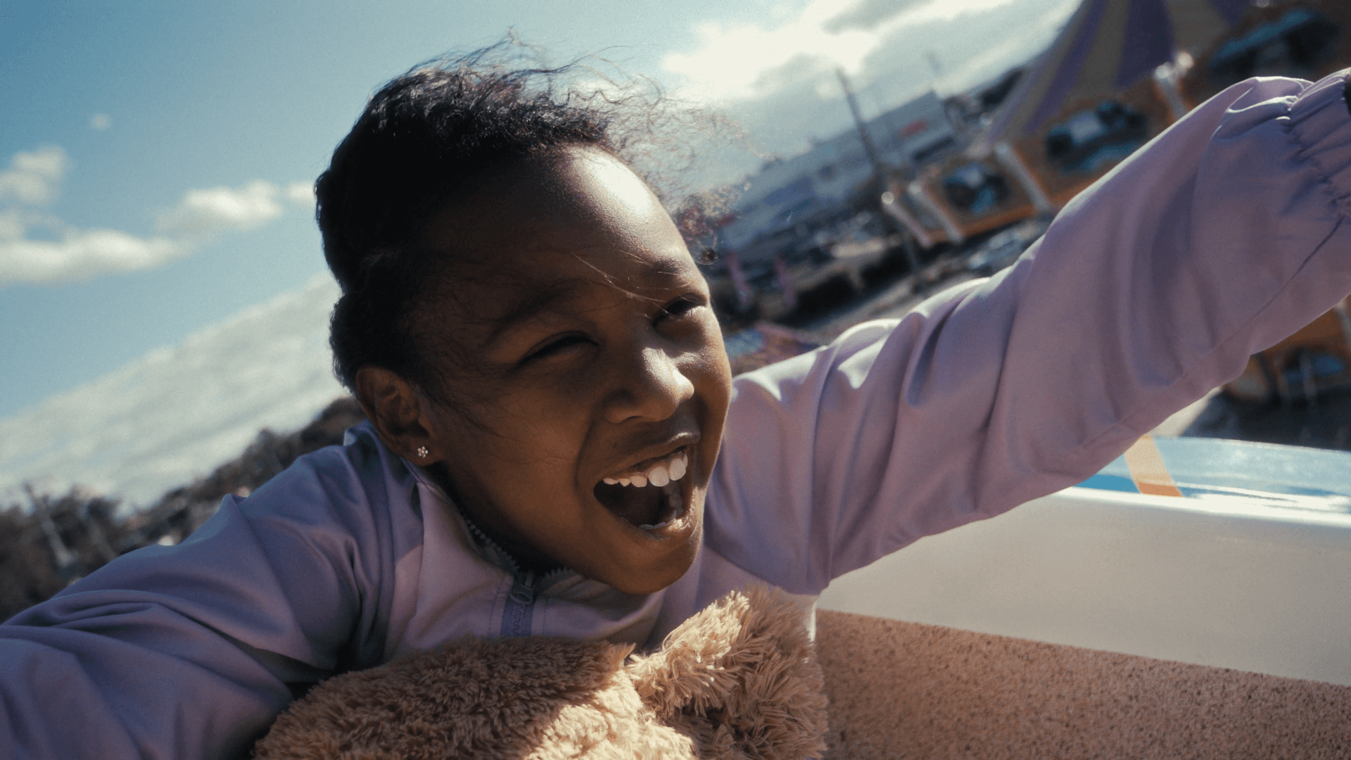 A happy little girl riding a roller coaster.