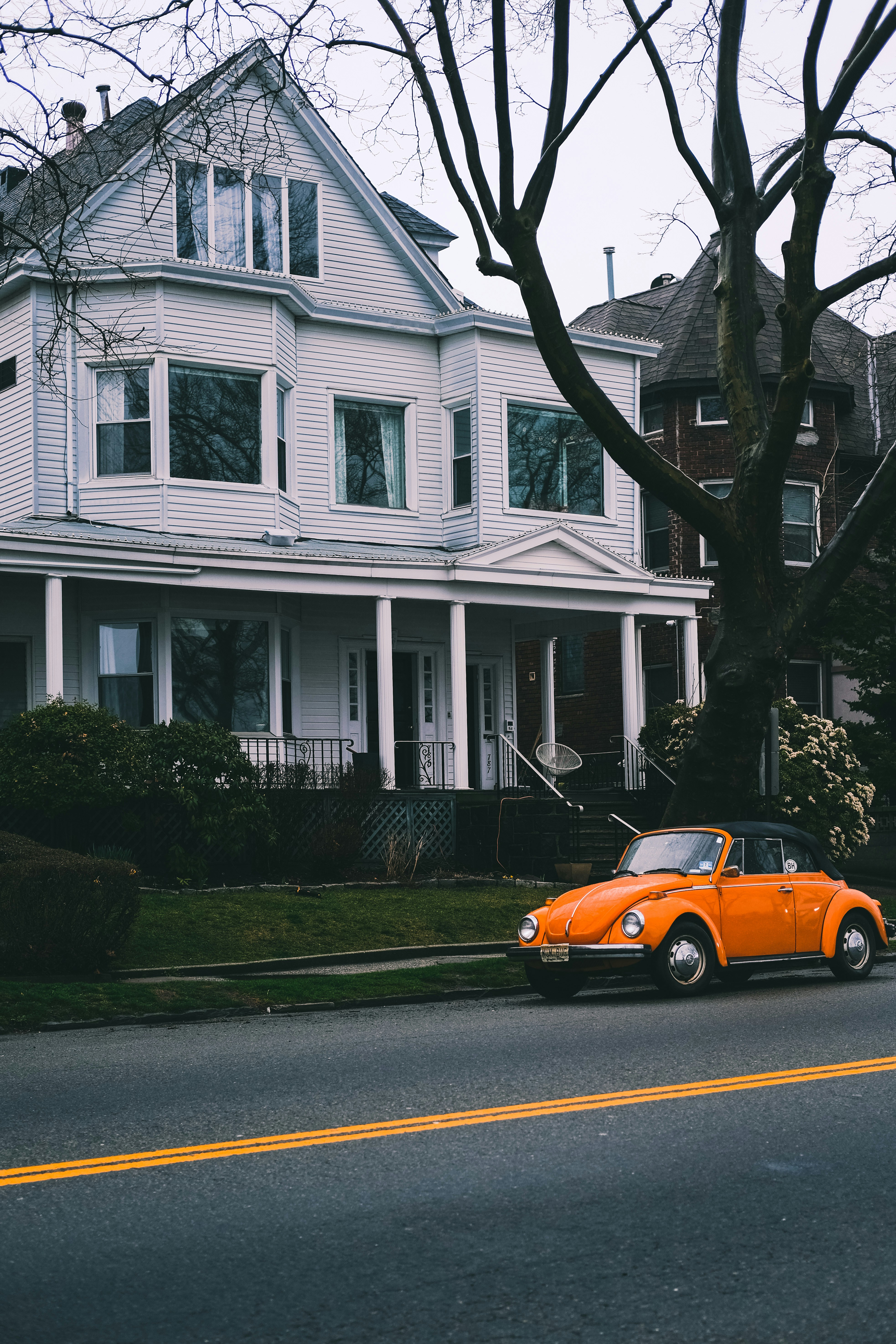 orange car parked in front of white and brown house