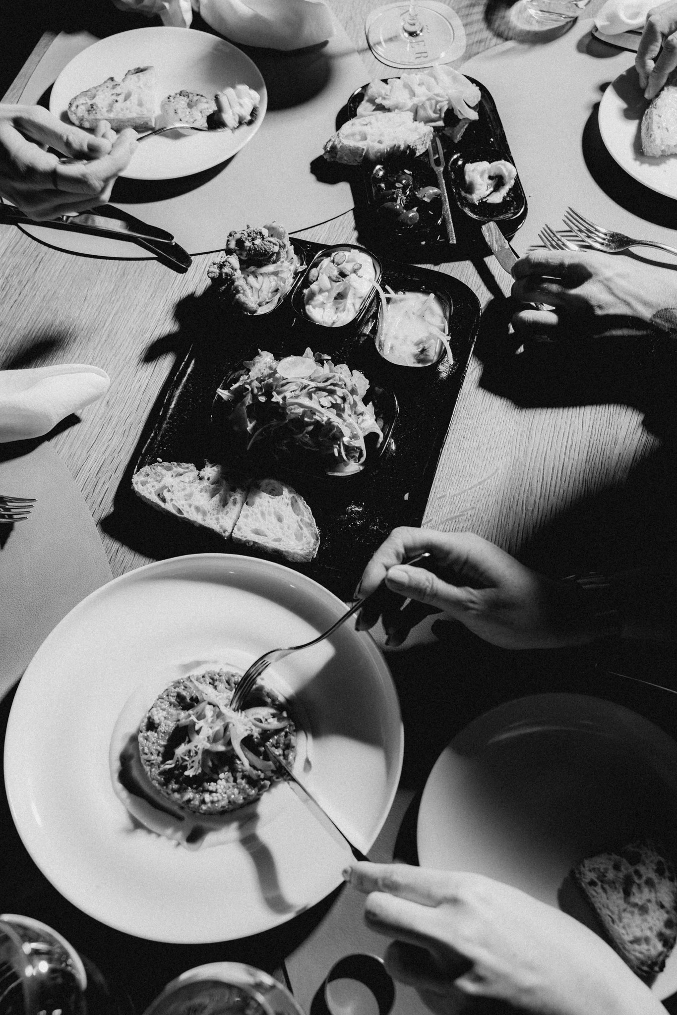 Schwarz-Weiß-Fotografie von mehreren Personen, die gemeinsam verschiedene Gerichte genießen, mit dem Schriftzug 'FOODIES'