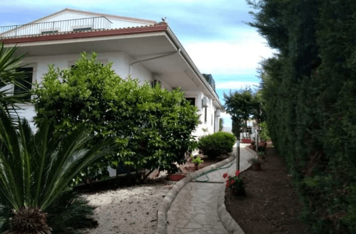 A modern brick house with a two-car garage, well-manicured lawn, and clear blue sky in the background.