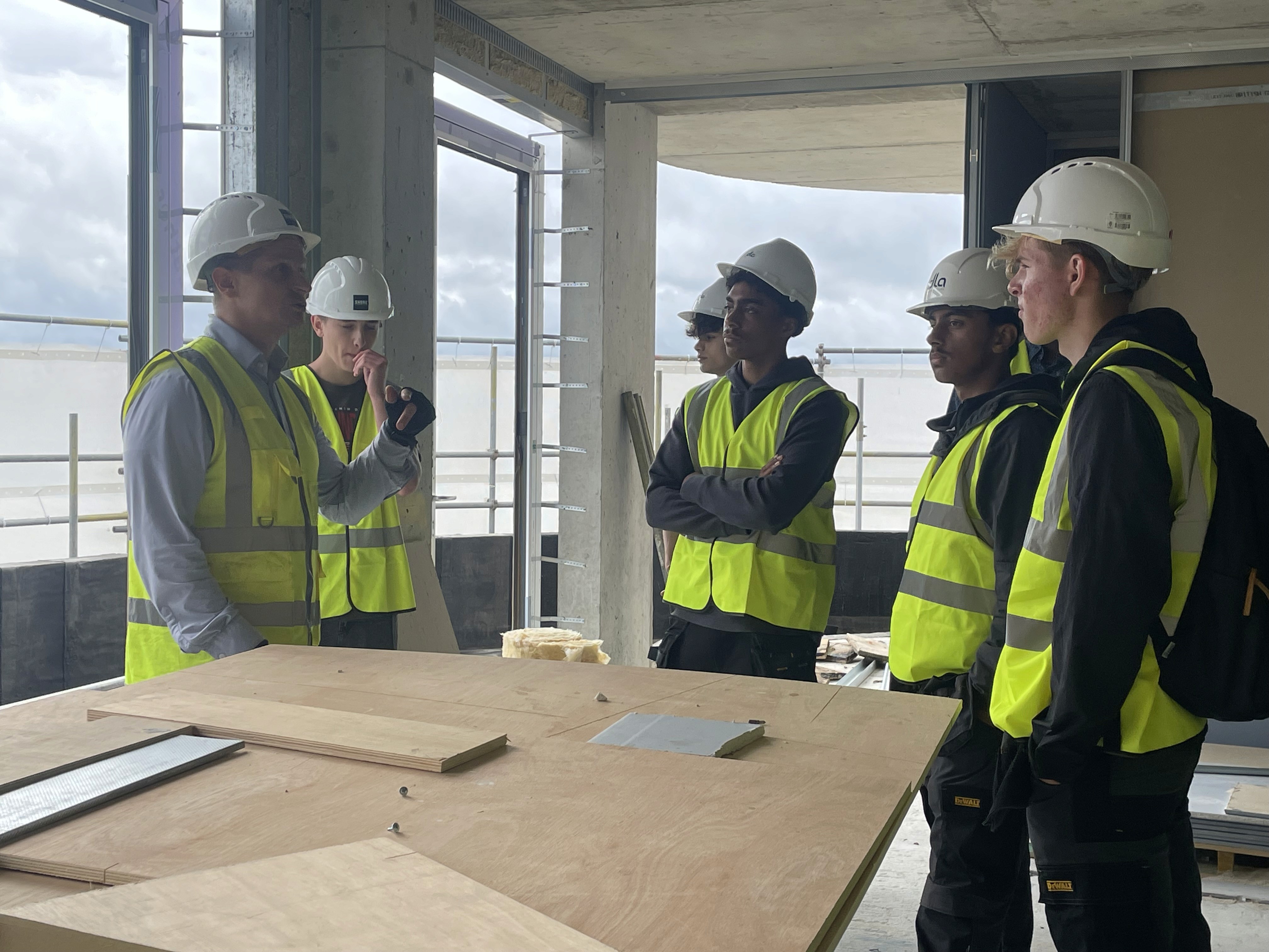 Construction engineers conducting a site meeting inside an unfinished commercial building to review project progress, construction quality, and workplace safety.