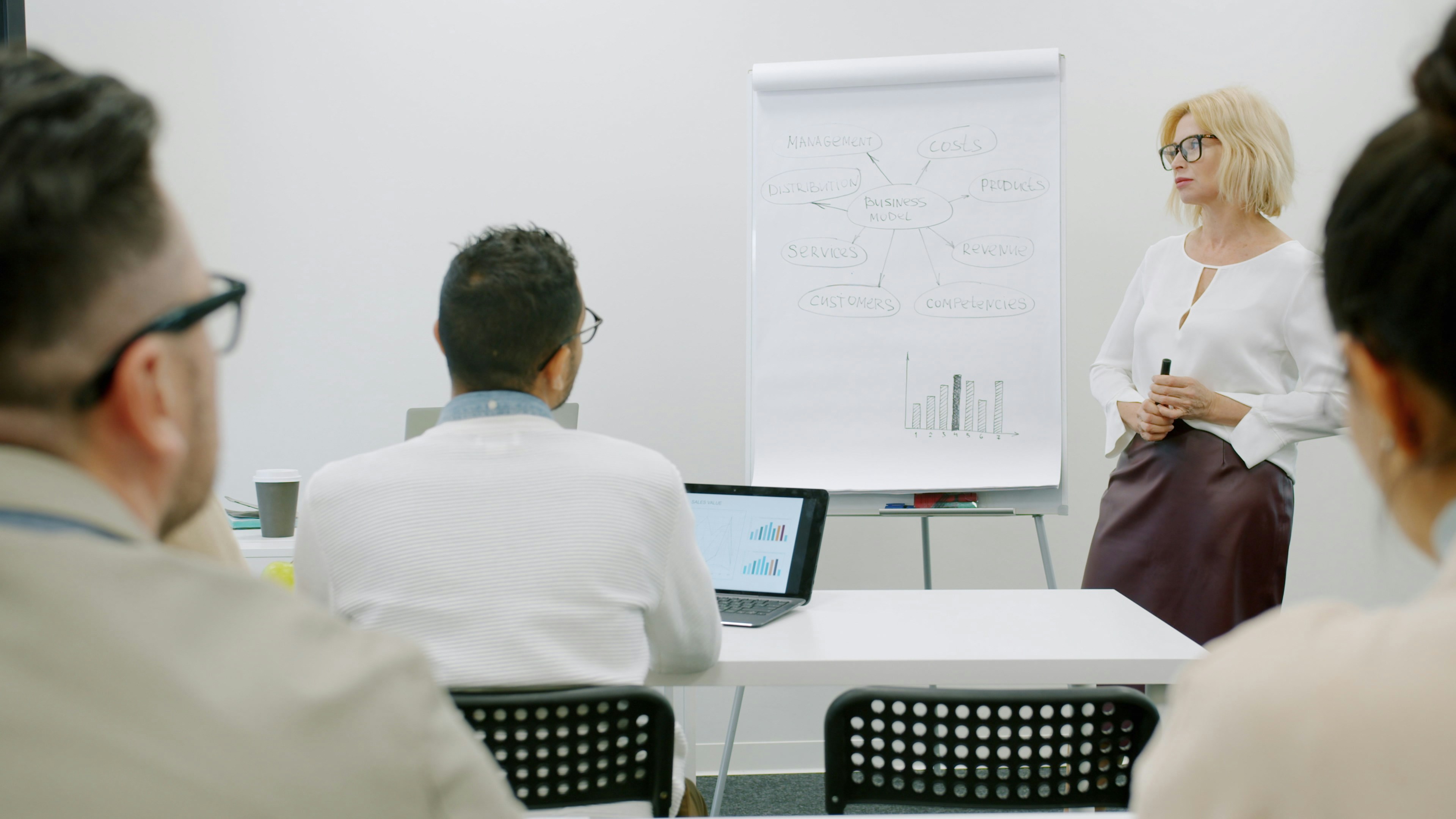 Woman presenting to audience in a modern office setting.