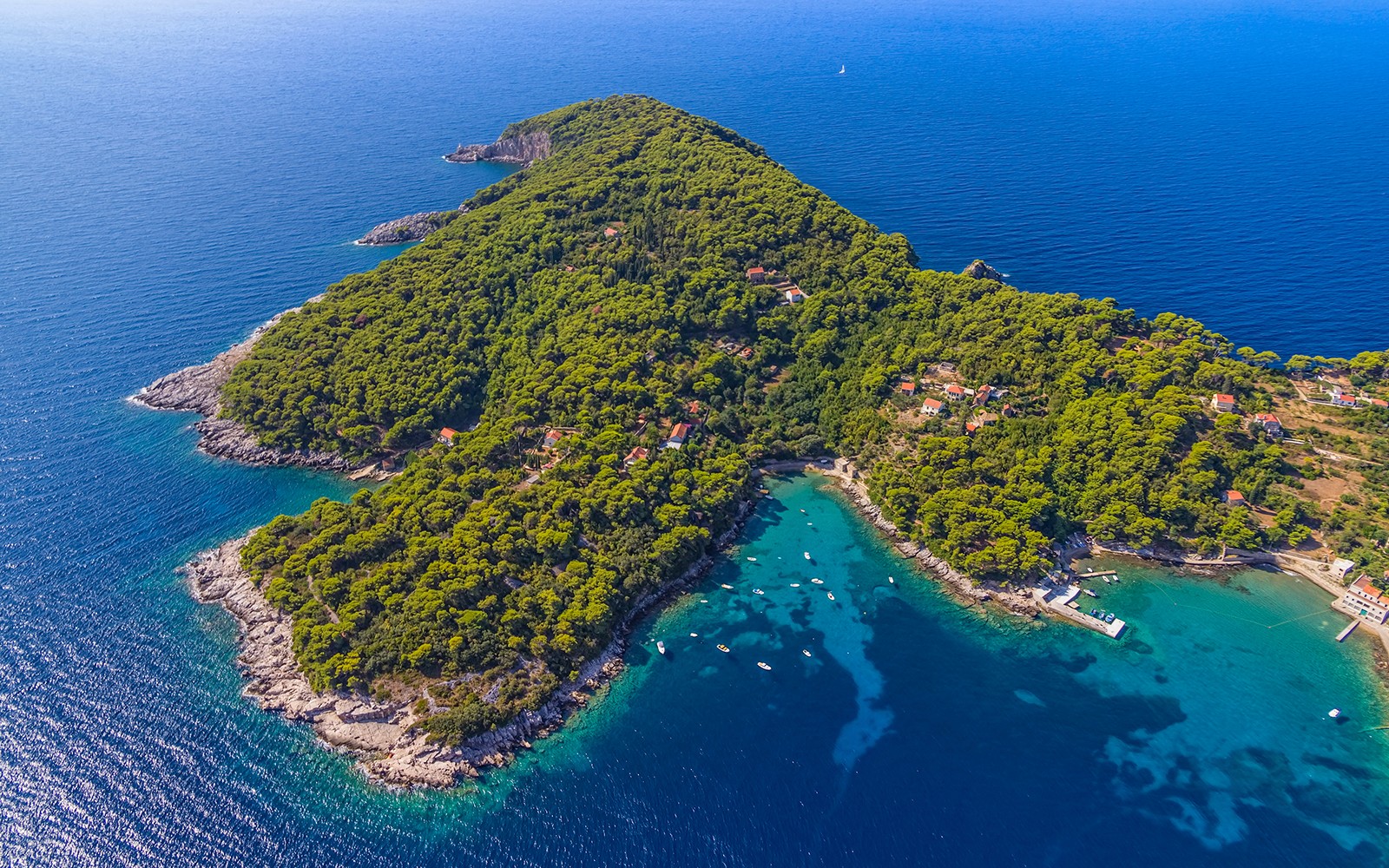 Aerial view of lush green island with boats in turquoise waters, Elaphites, Dubrovnik.