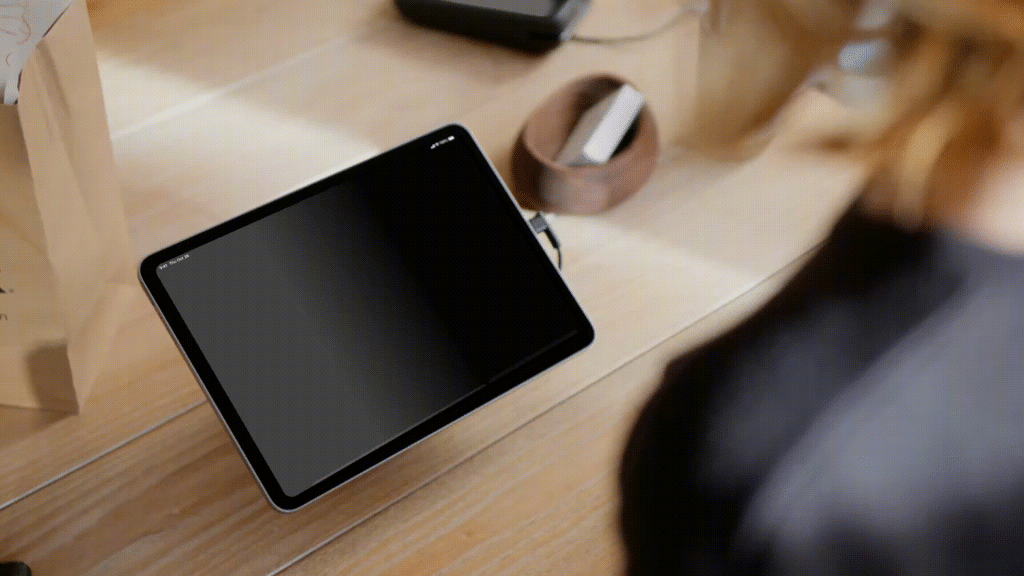 Tablet op een standaard op een houten winkeltoonbank, gebruikt als Shopify POS-kassa in een winkel