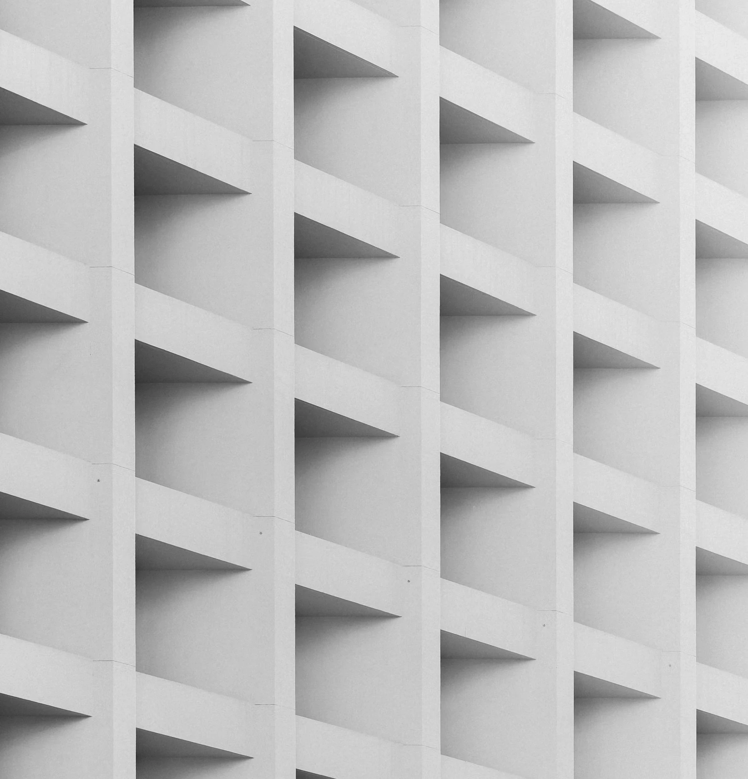 Minimal white architectural facade with a repeating grid of recessed rectangular forms