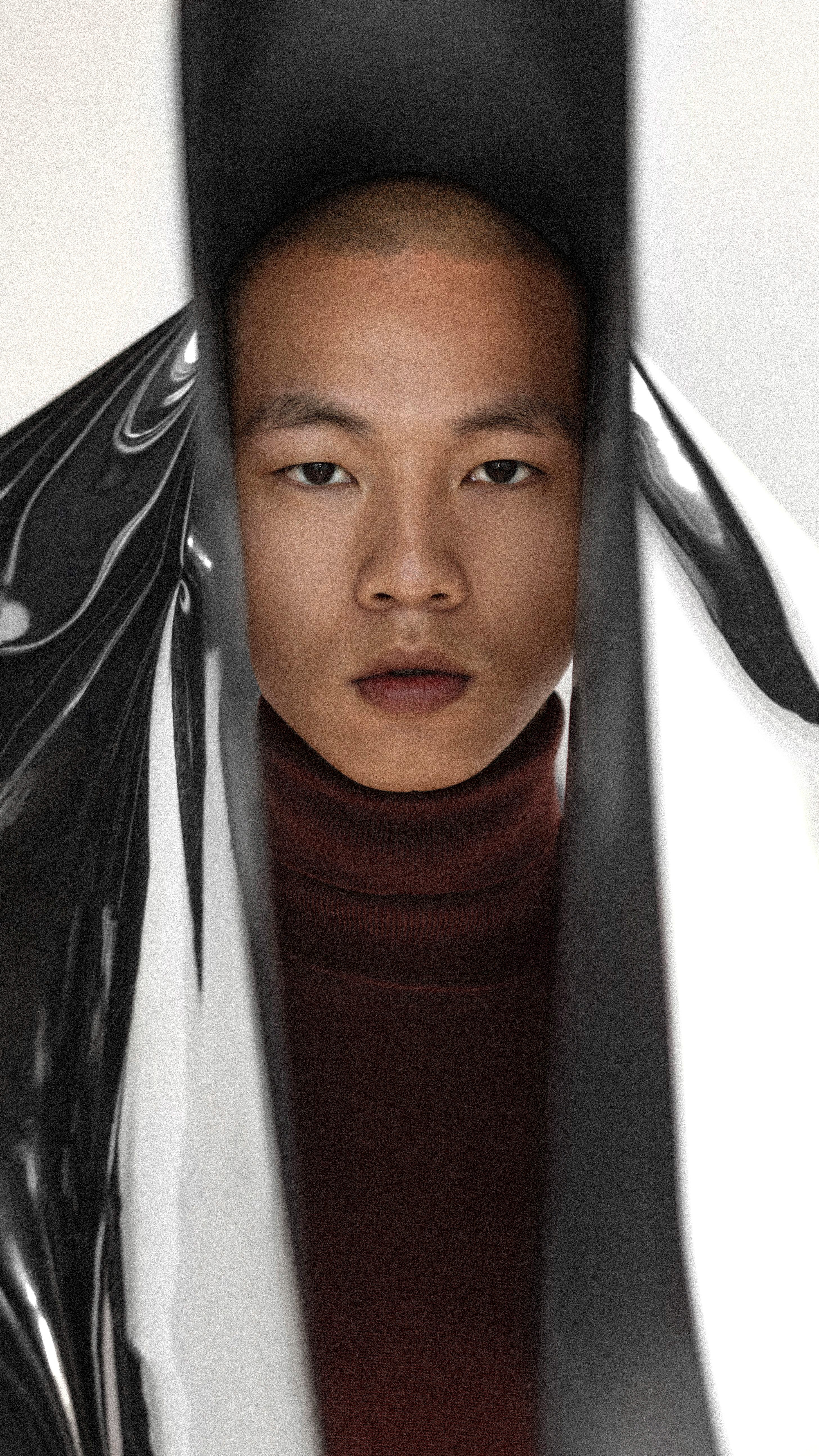 Confident young Asian man looking at the camera against a white background with reflective artistic elements.