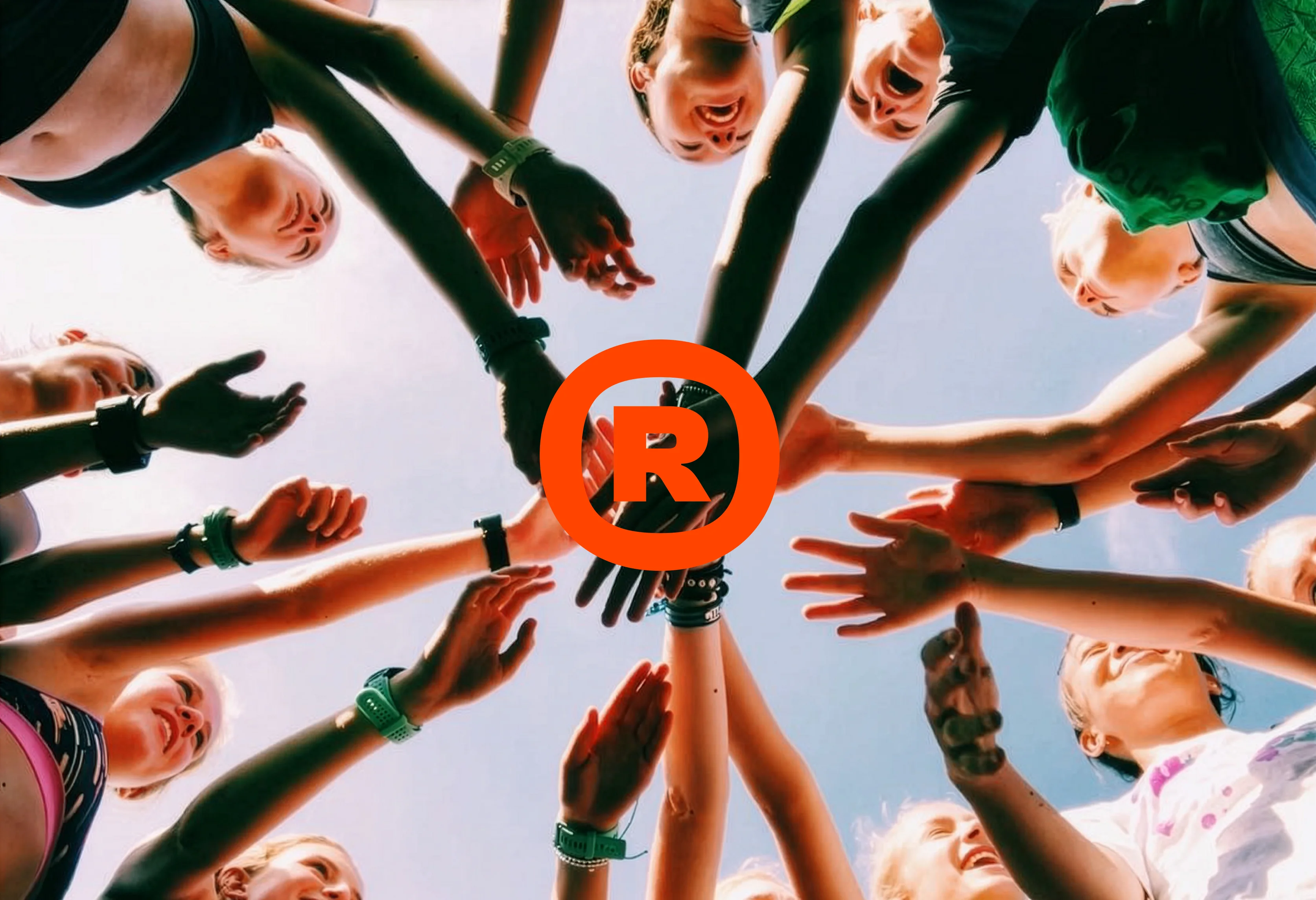 Many hands form a circle around a bright orange R logo.