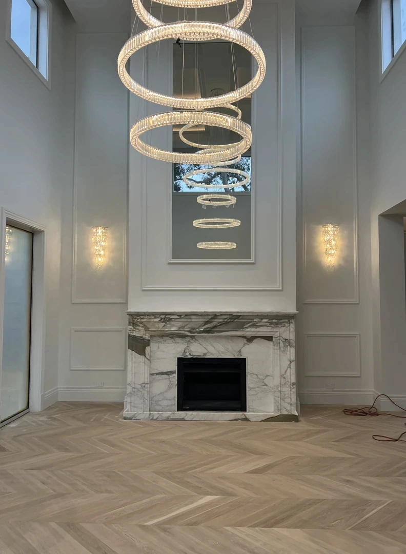 Natural stone fireplace feature wall with marble cladding, modern lighting, and formal interior setting.