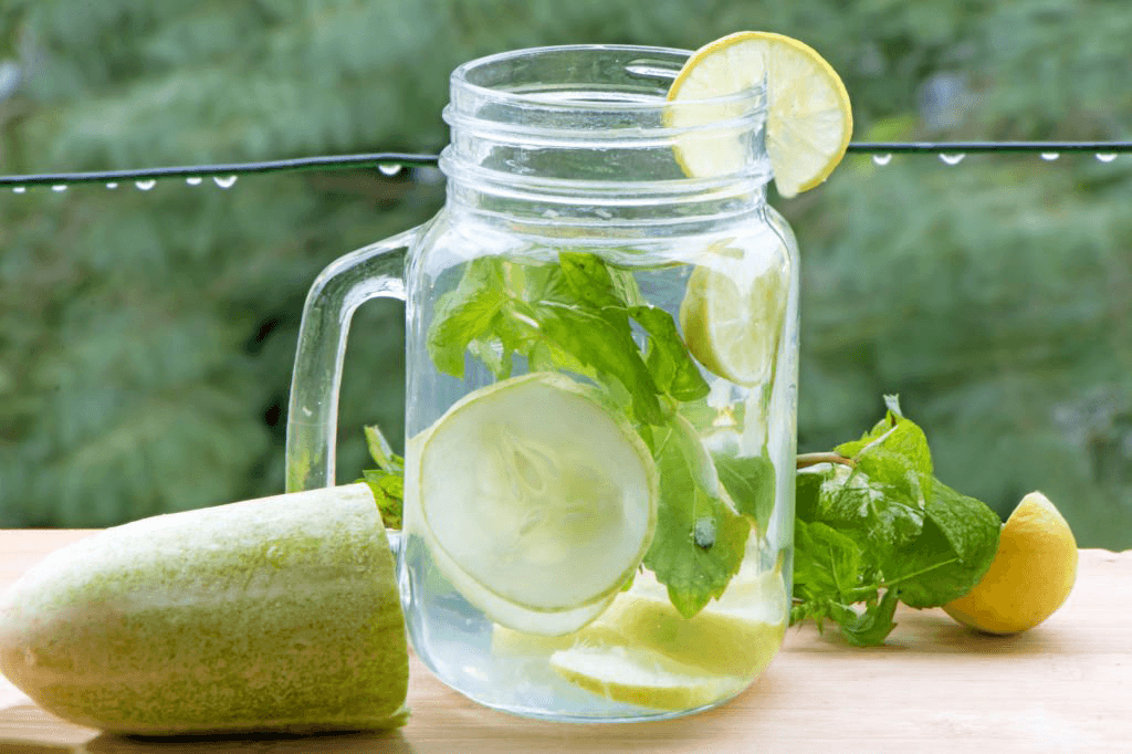 Hydrating cucumber and lemon detox water in a glass jar with fresh mint and lime slices.