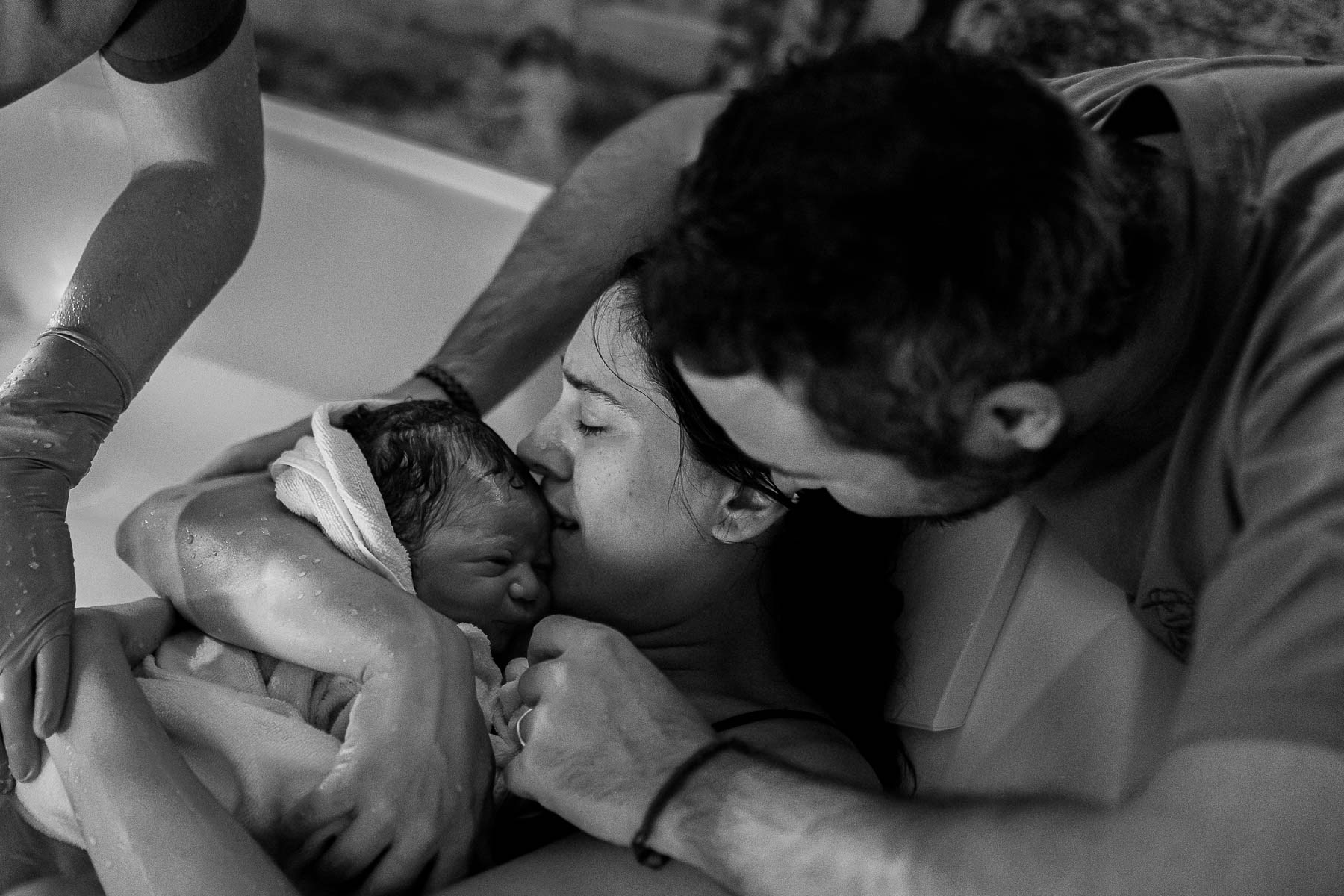 Mujer en trabajo de parto en casa, acompañada por su pareja, parto en piscina, fotografía documental en blanco y negro.