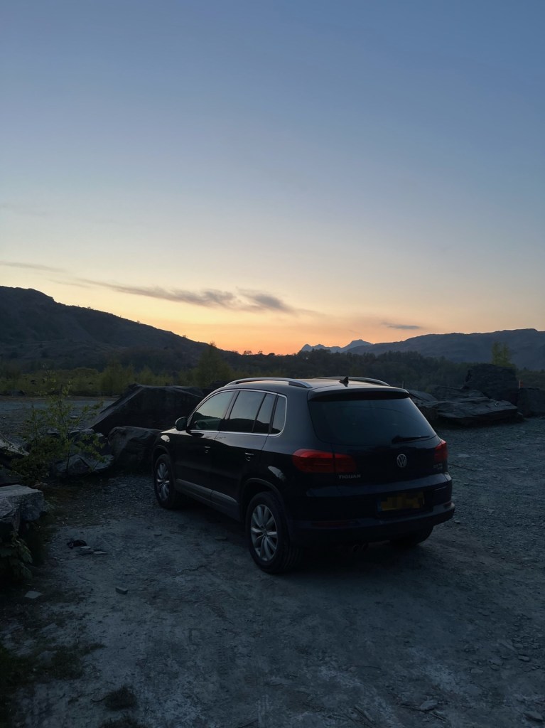 Our black VW Tiguan in the dark, with a soft glow of the remaining sunset in the background.