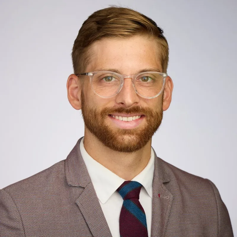 image of Gabriel Oland, MD in a brown suit with a teal and red tie
