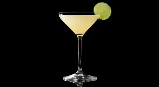 A closeup of a Kamikaze drink against a dark background.