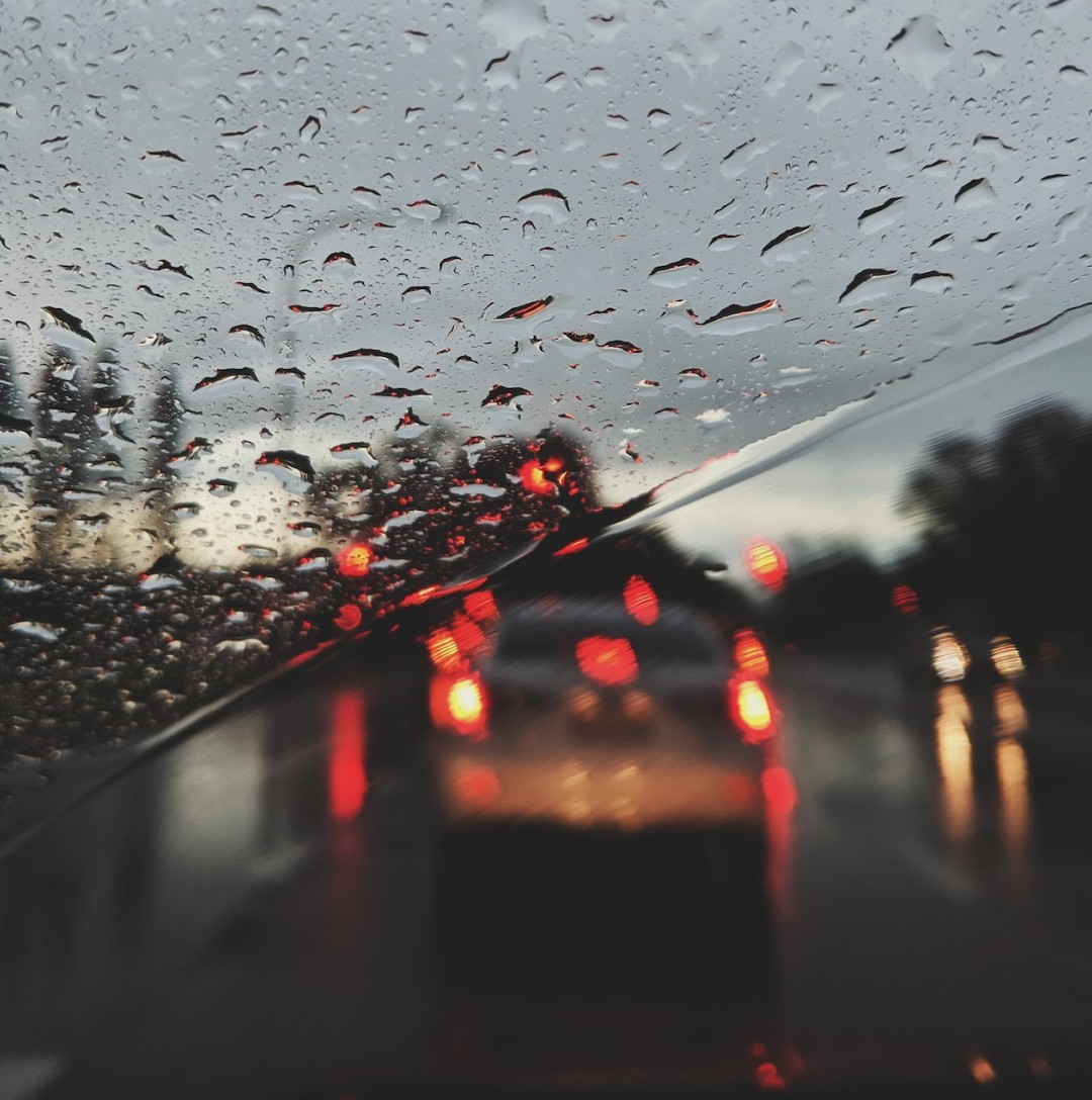 Image of a unfocused car in the road. Rainy day.