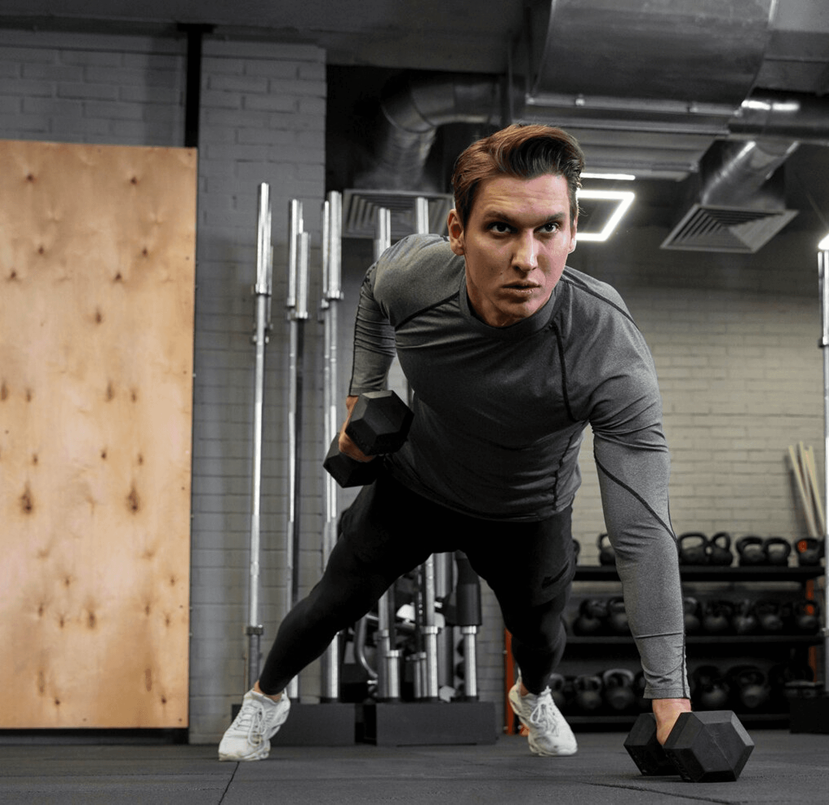 Man doing a dumbbell plank row in a gym.