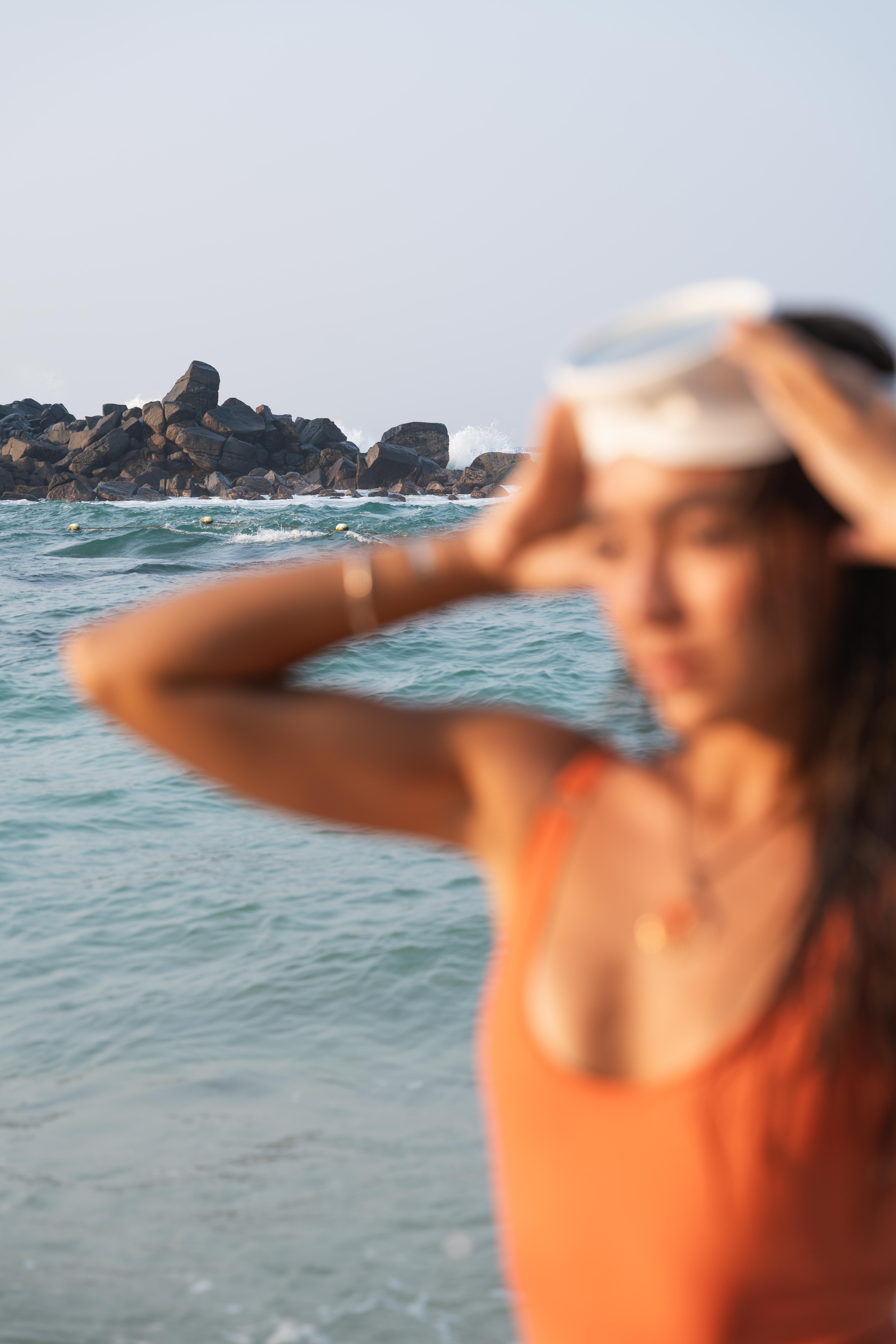Blurry girl in orange bathing suit in the front and ocean view in the back 