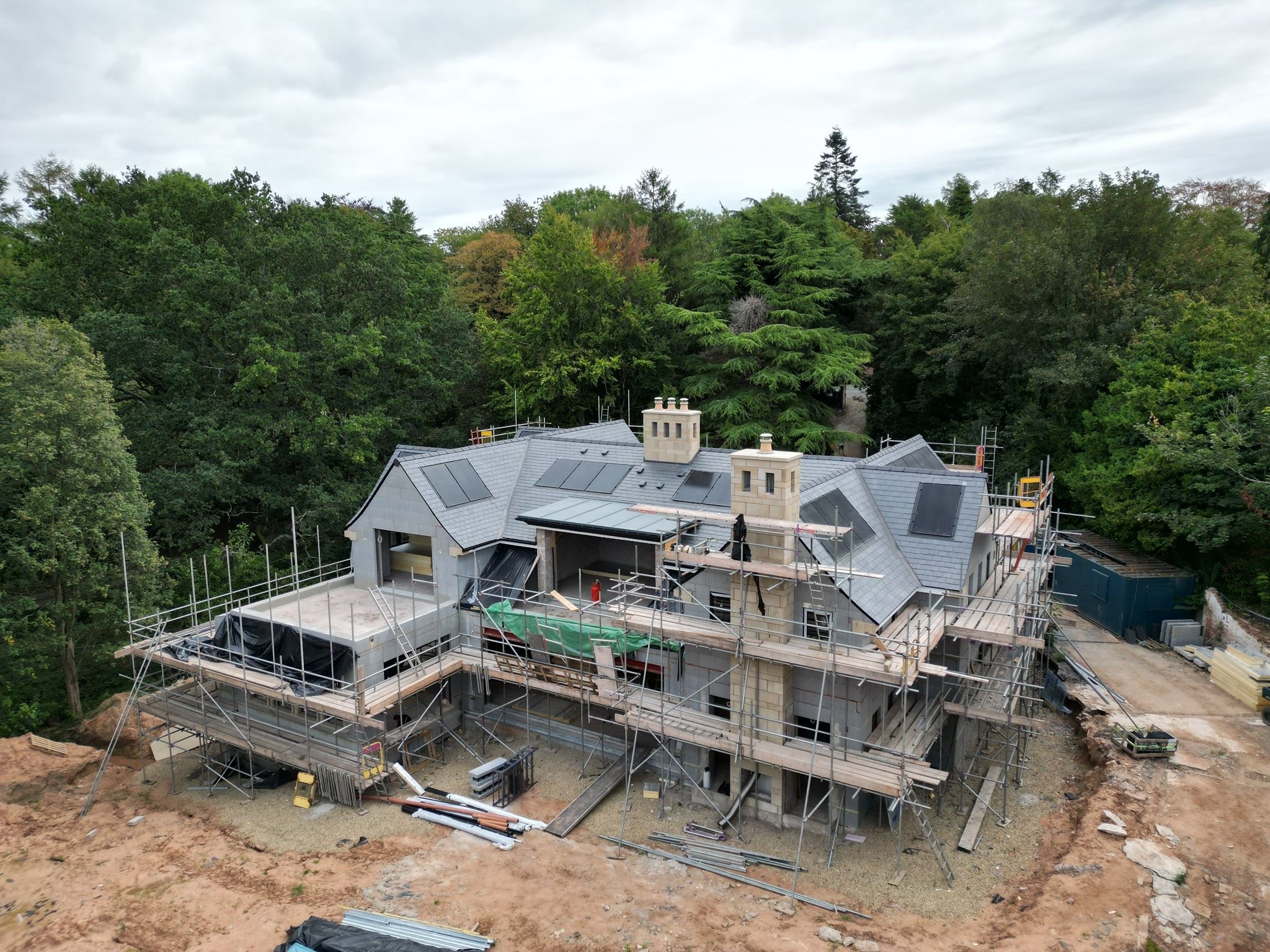 A smiling man with curly hair is sitting at a desk, looking at the camera, with a laptop and a lamp in the background.