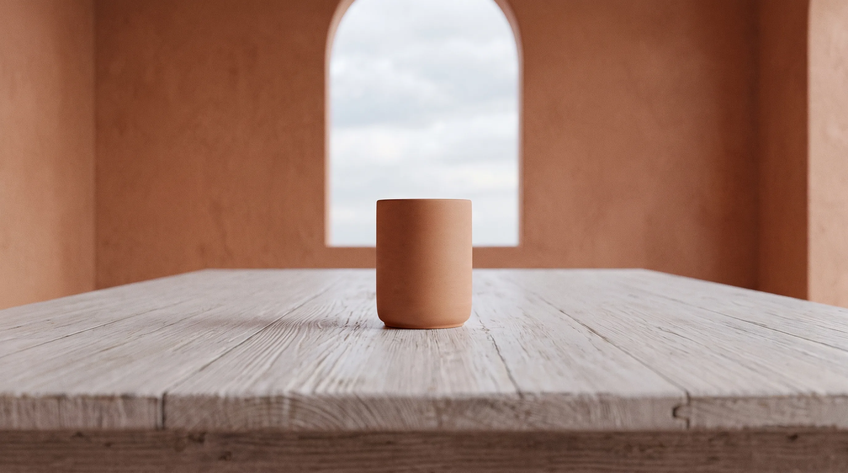 A single ceramic vessel alone at the centre of a bare whitewashed table