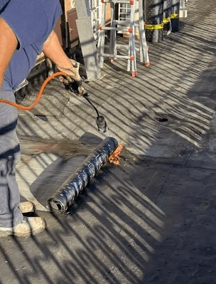 operaio scalda guaina impermeabilizzante con cannello a gas butano