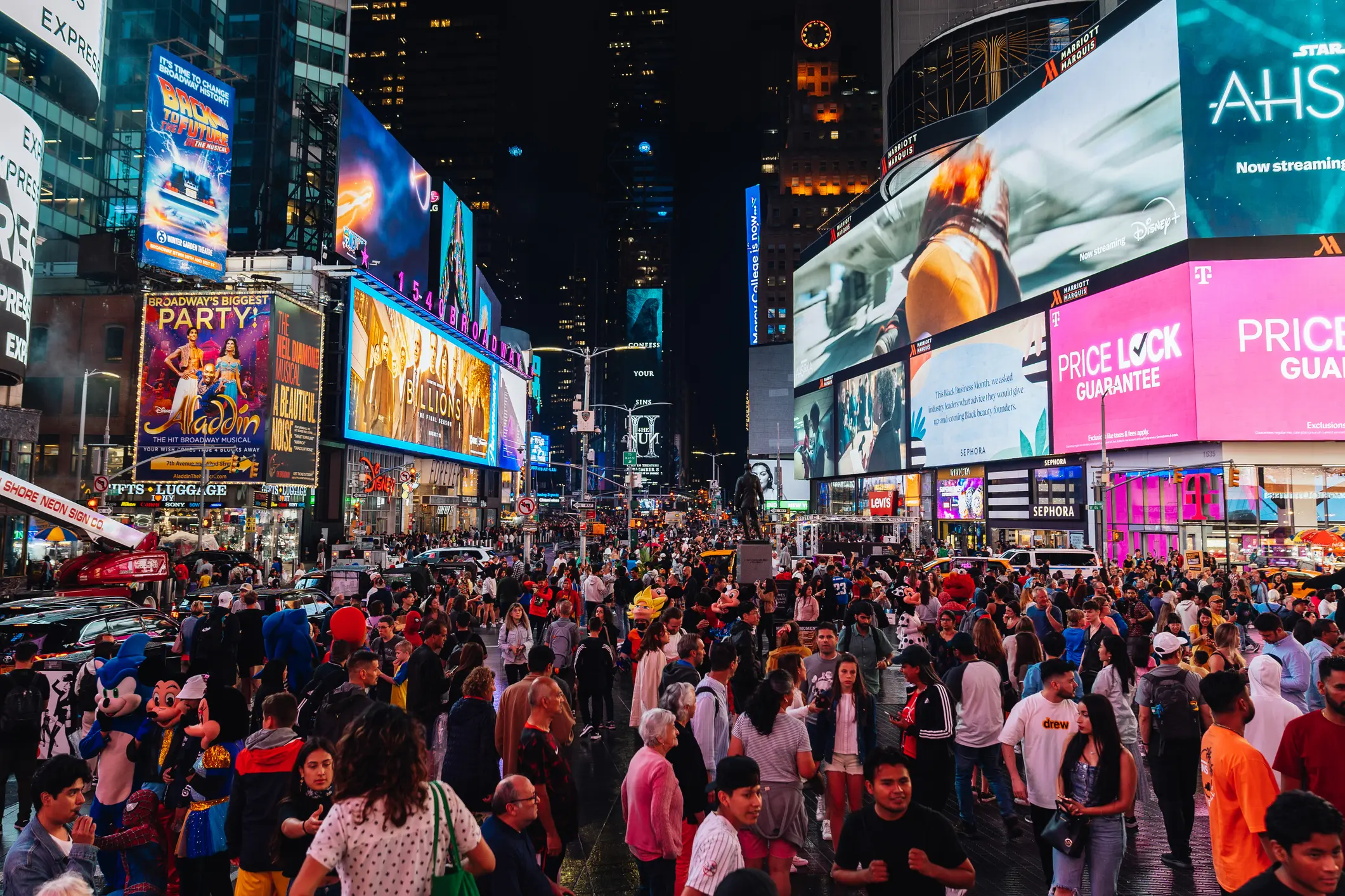 Crowded Times Square at night surrounded by competing brand billboards and digital advertising displays
