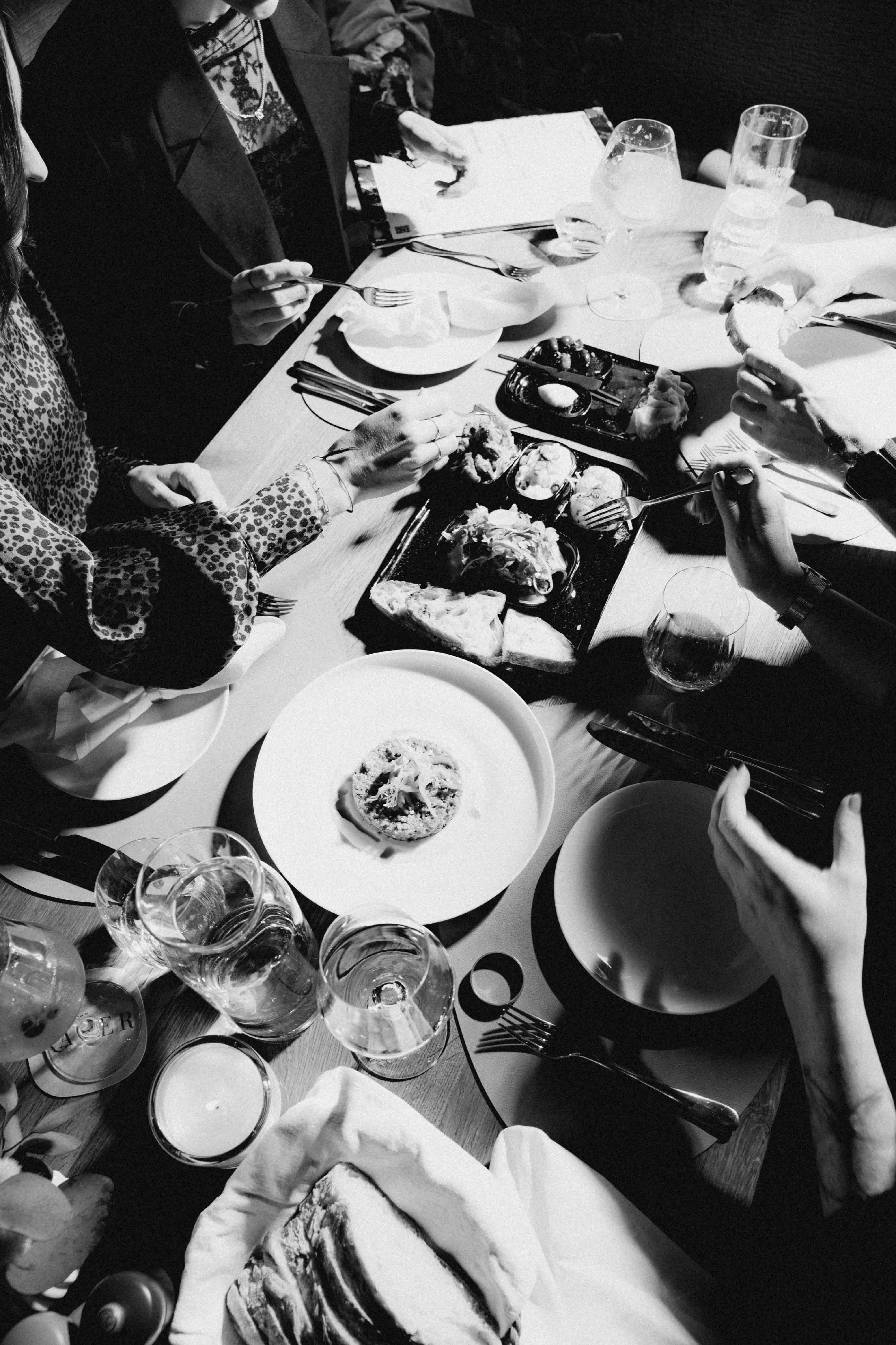 A black and white close-up of a table covered with various plates of food.