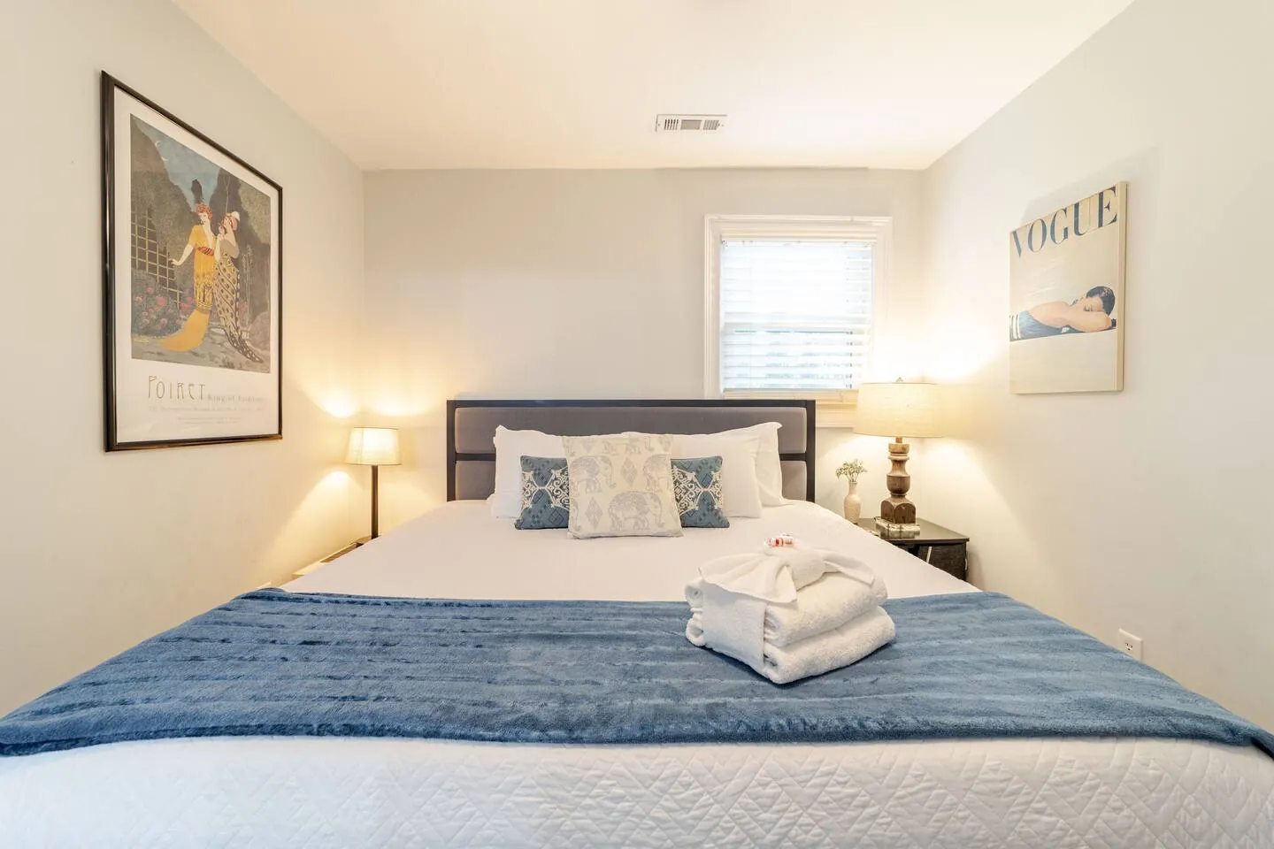 Bedroom with a navy throw, a vintage poster and a Vogue print