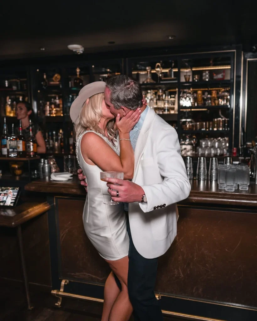 Wedding guests kissing in front of a bar