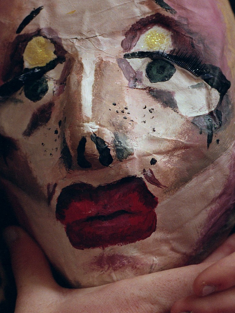 "Paper-mâché mask held in a hand"