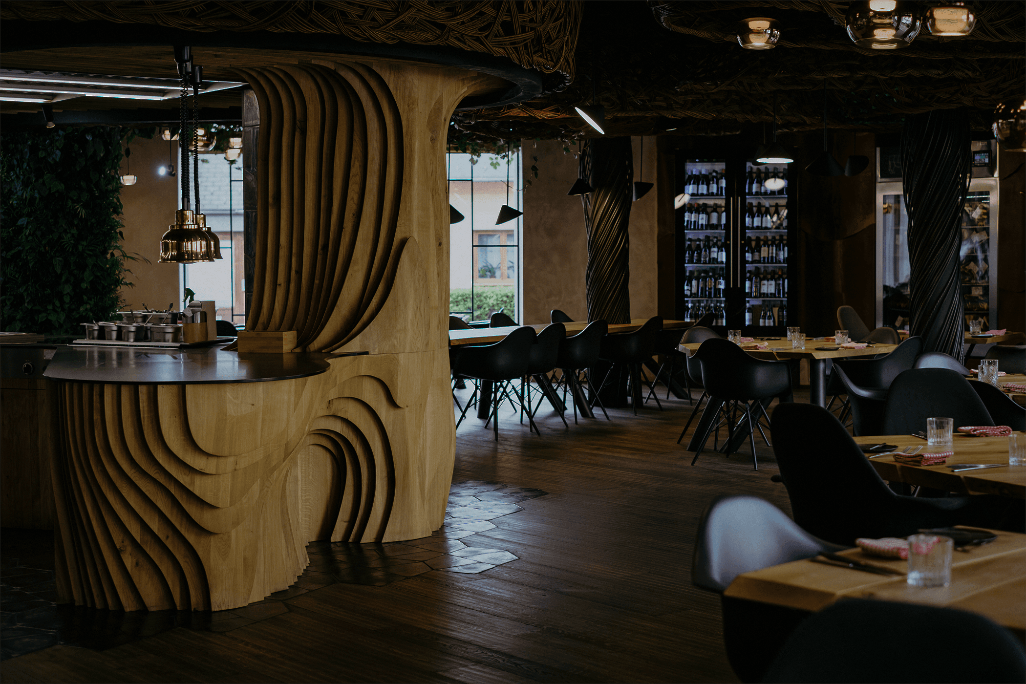 Stylový interiér moderní restaurace s originálním dřevěným designem, kulatými prvky a černými židlemi.