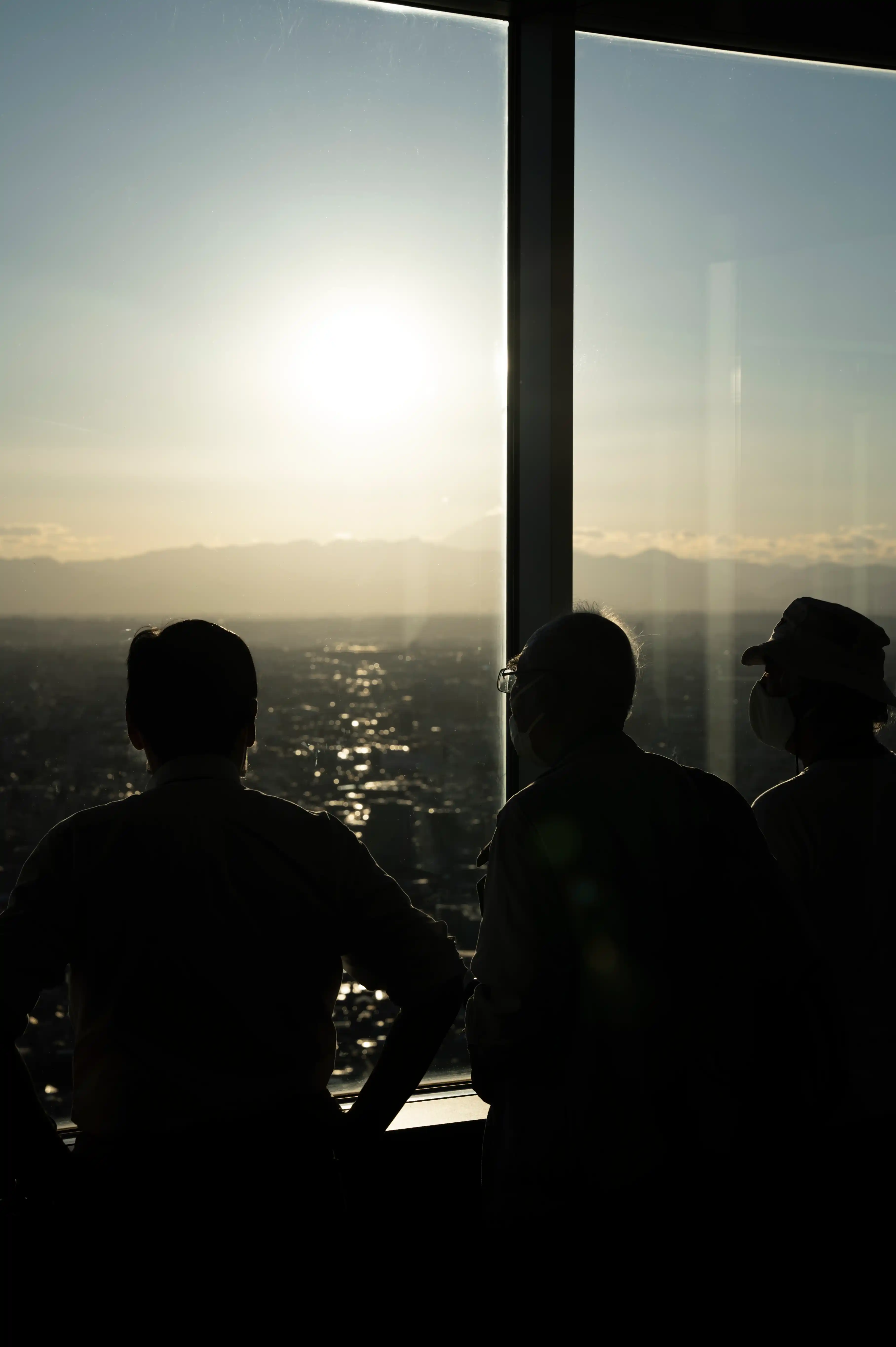 Silhouette of a team looking out at a city skyline during sunset.